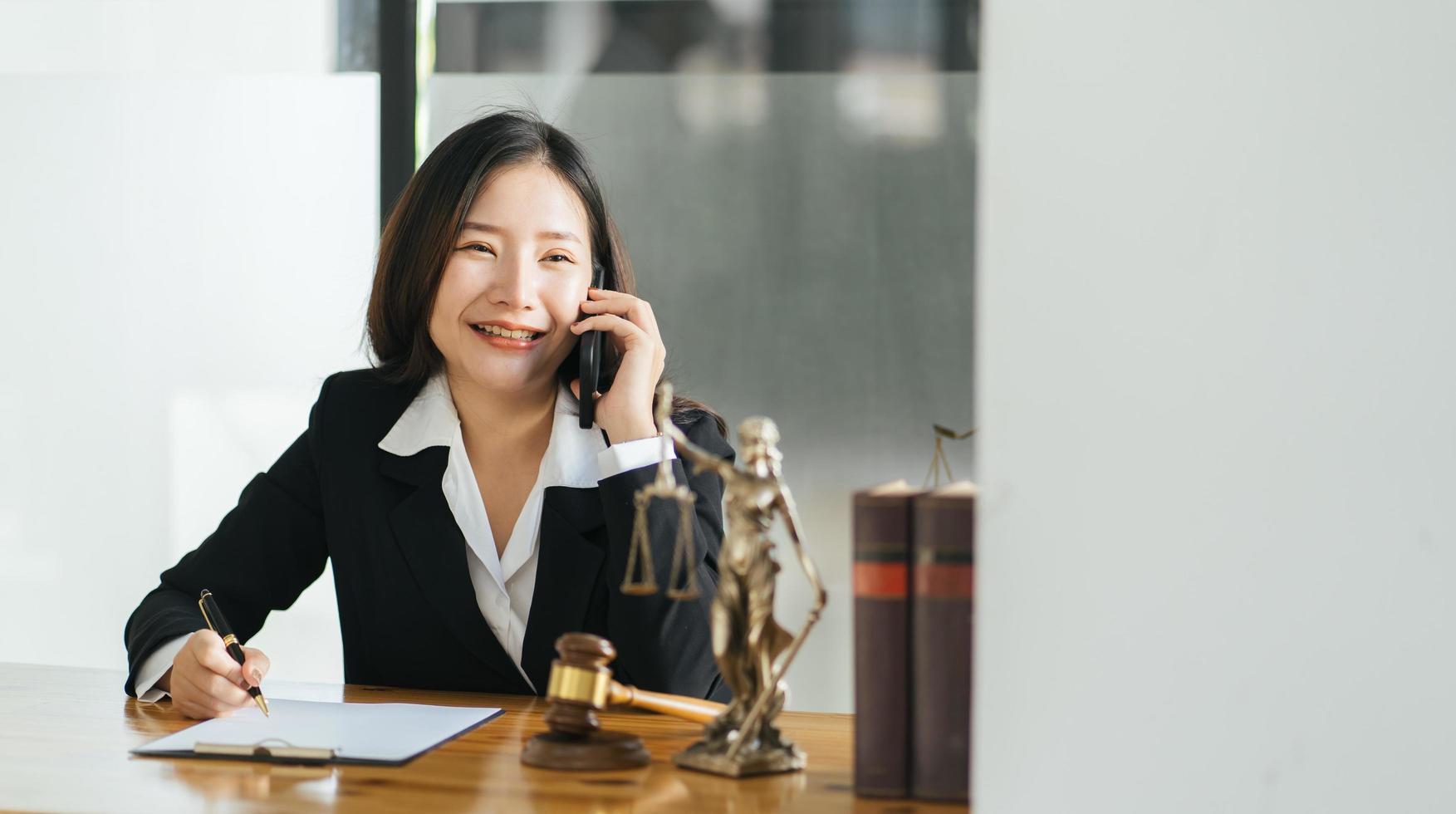 Young beautiful Asian woman lawyer who working in the office. Tlaking on a smart phone with client. photo