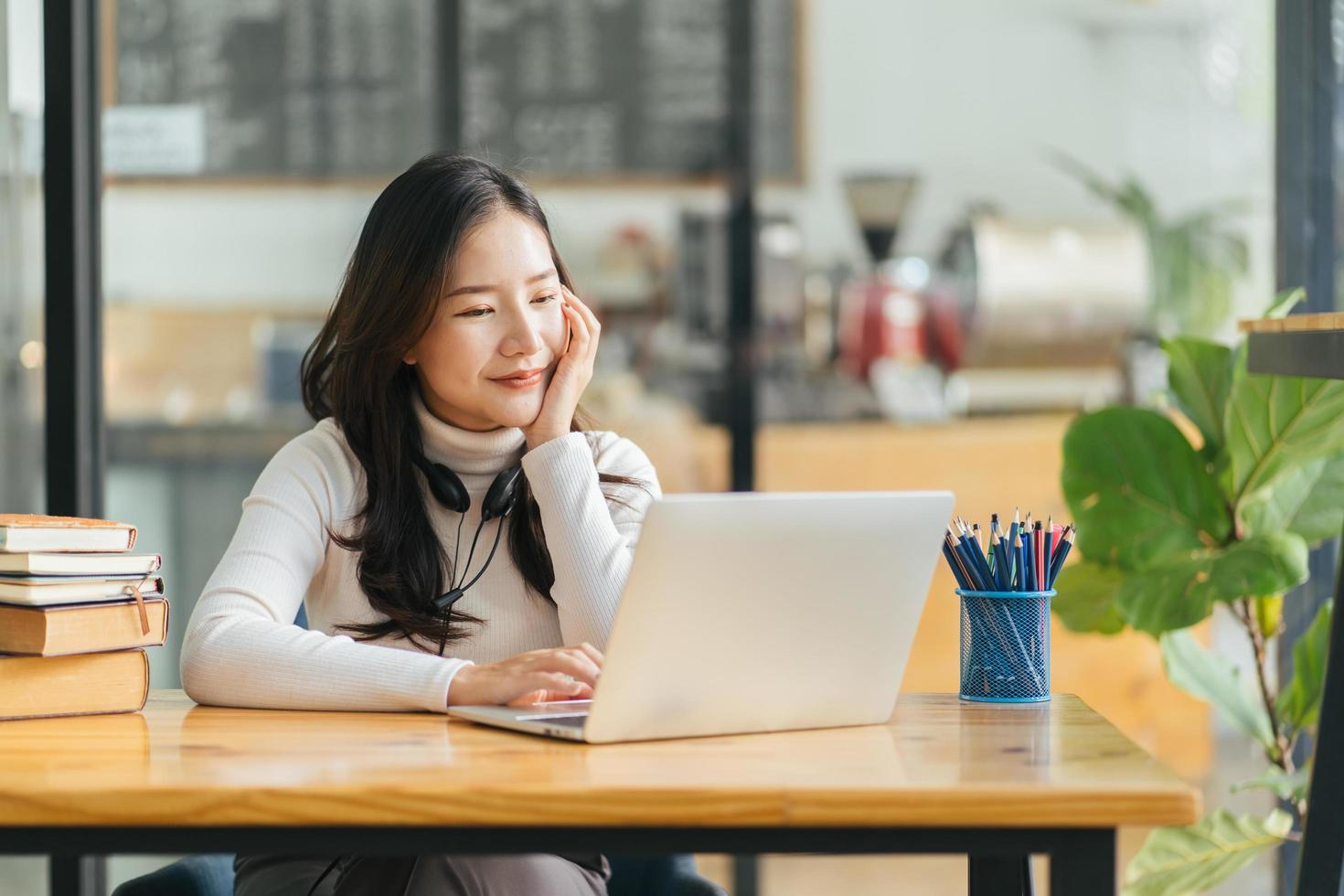 imagen de una joven hermosa mujer alegre sonriendo mientras trabaja con una laptop en la oficina foto