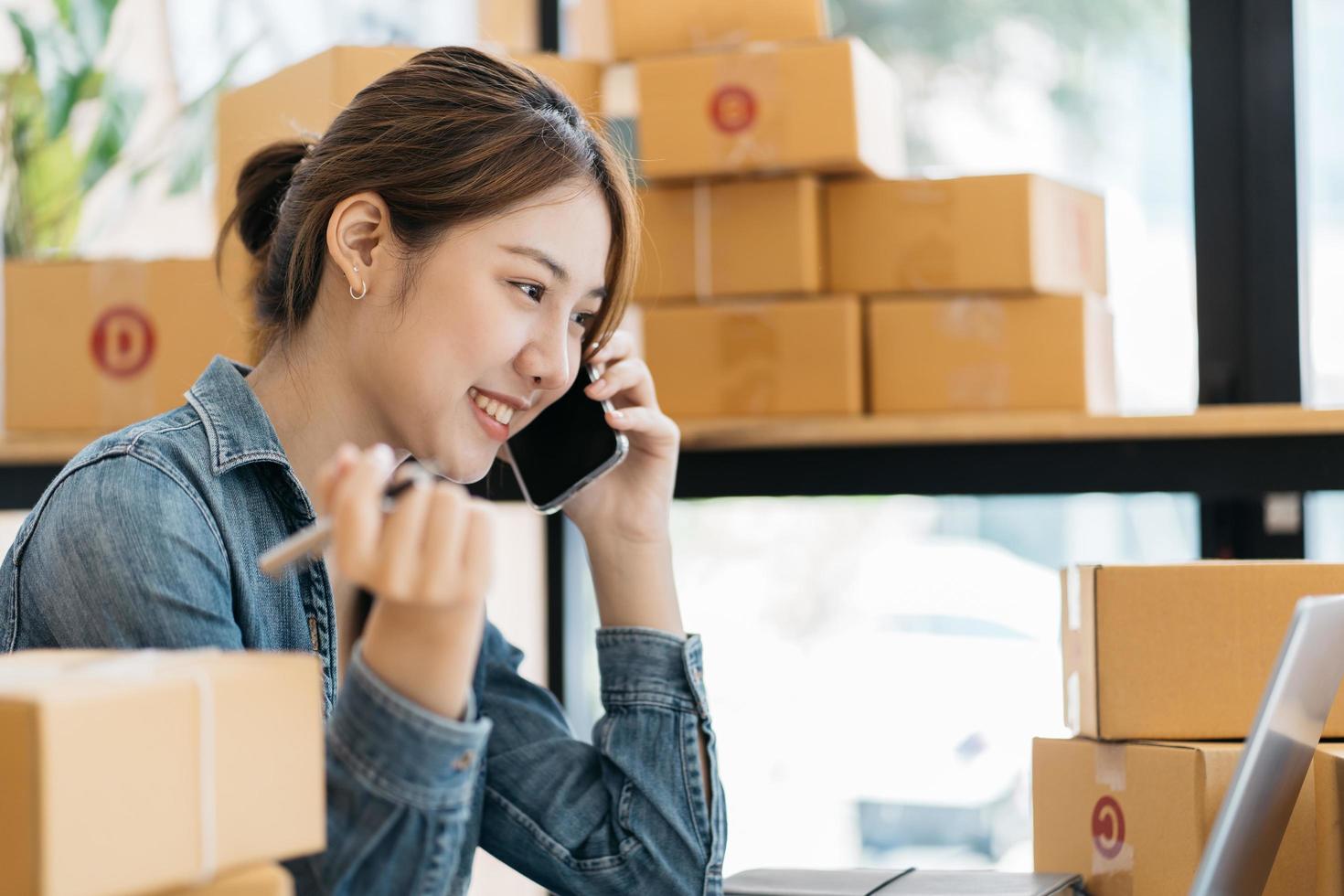 emprendedor de pequeñas empresas, autónomo, retrato de mujer joven que trabaja en la oficina en casa, caja, teléfono inteligente, computadora portátil, en línea, marketing, empaque, entrega, pyme, concepto de comercio electrónico foto