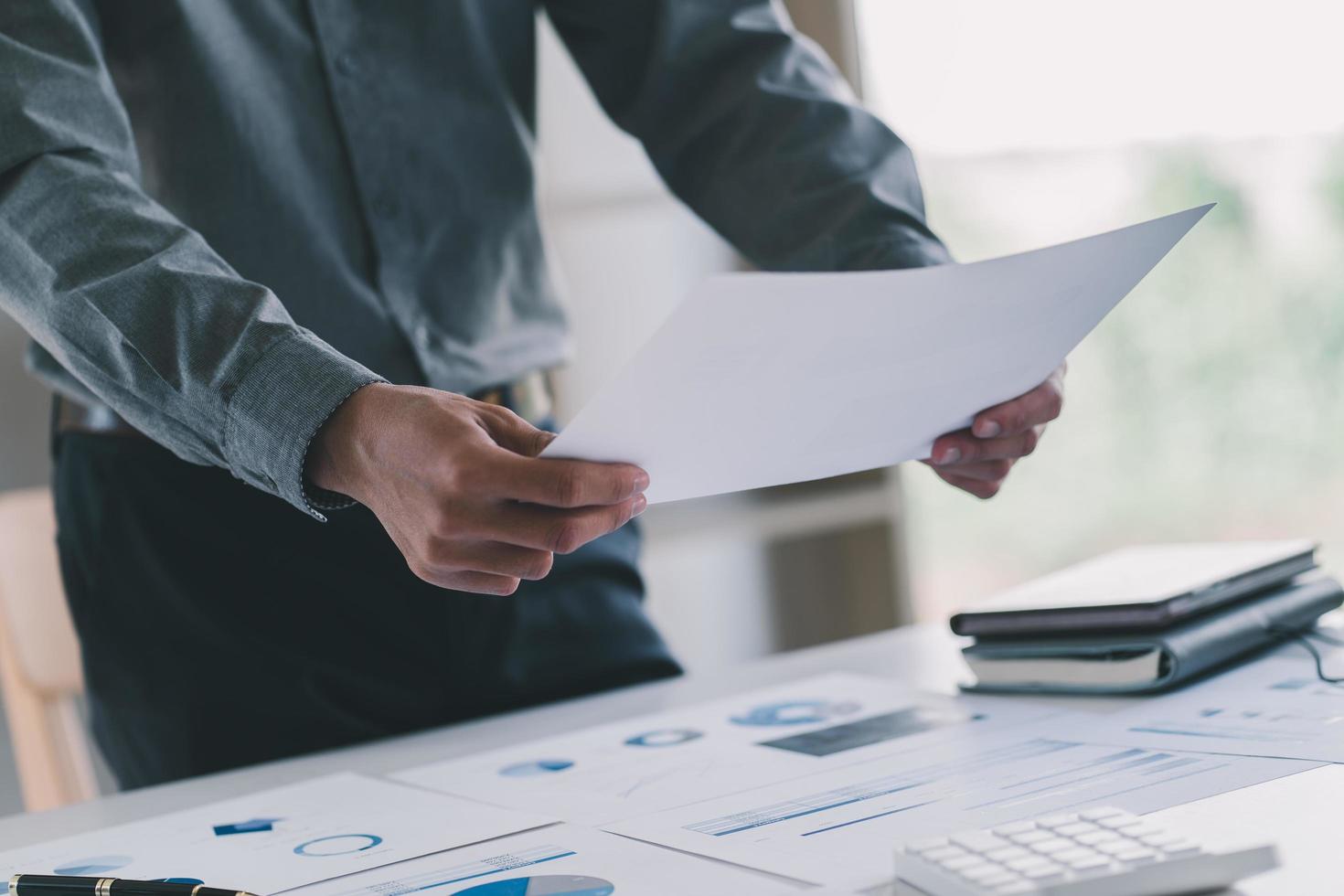 Primer plano de la mano del hombre de negocios trabajando en el diagrama de información gráfica en el escritorio de madera como concepto foto