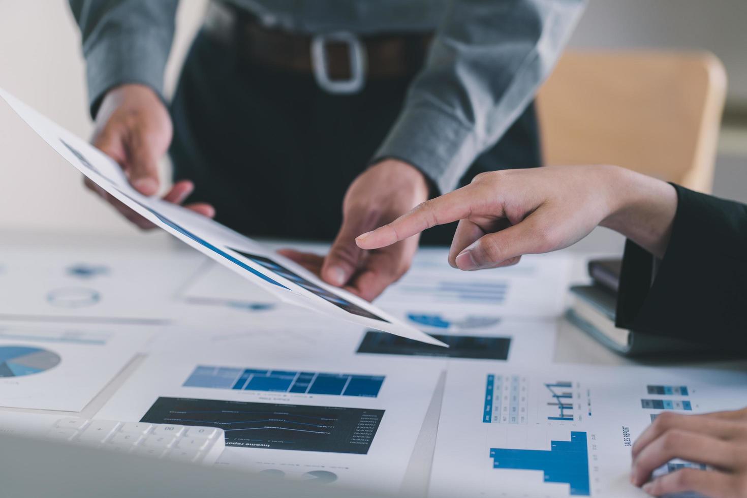 Close-up of Businessman hands pointing at turnover graph while discussing it on wooden desk with pen in meeting room, Business financial working concept, business people pointing at business document, photo