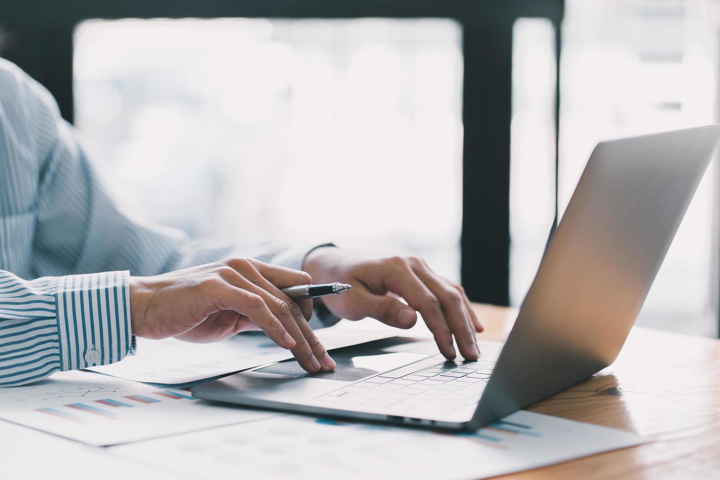 Businessman hand pressing on the laptop keyboard, World of technology and internet communication, Financial professionals use laptop to calculate and check real estate earnings. photo