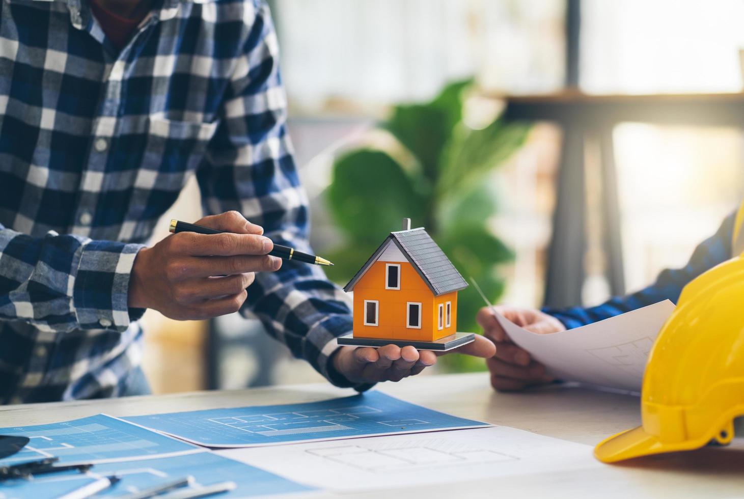 Architect and engineer meeting Planning for a New Project with construction equipment on table, Architect and engineer working with blueprint and house model. photo