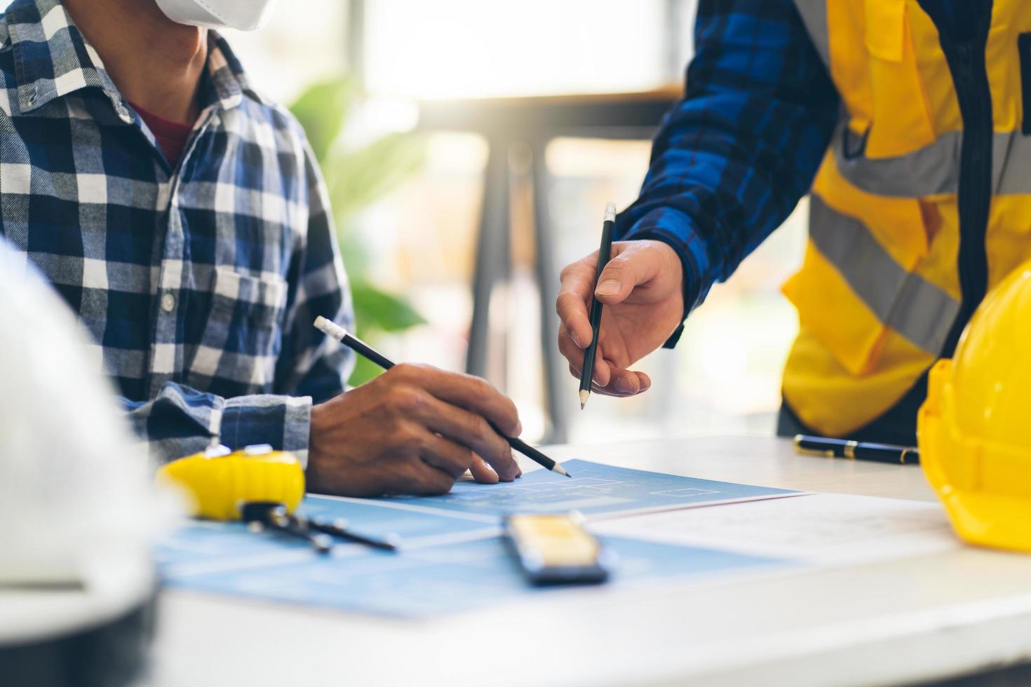 Engineer and Architect meeting working and pointing at a drawings in office for discussing. Engineering tools and construction concept,Engineers and Architects Brainstorm. photo