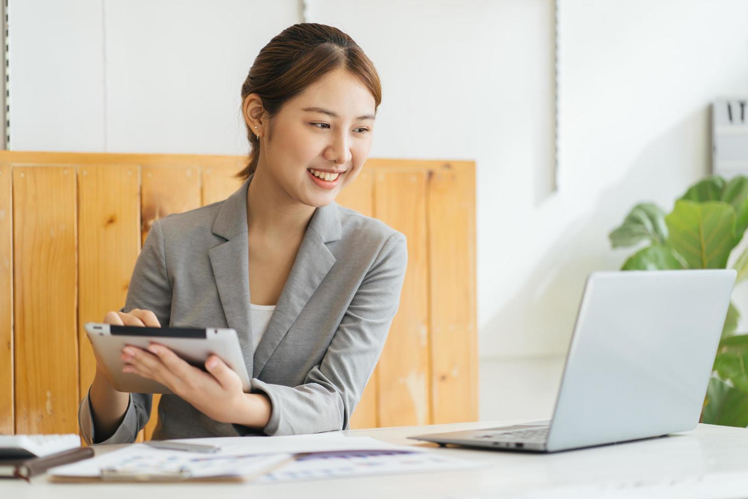 la joven empresaria asiática está feliz de trabajar en la oficina moderna usando una tableta. foto