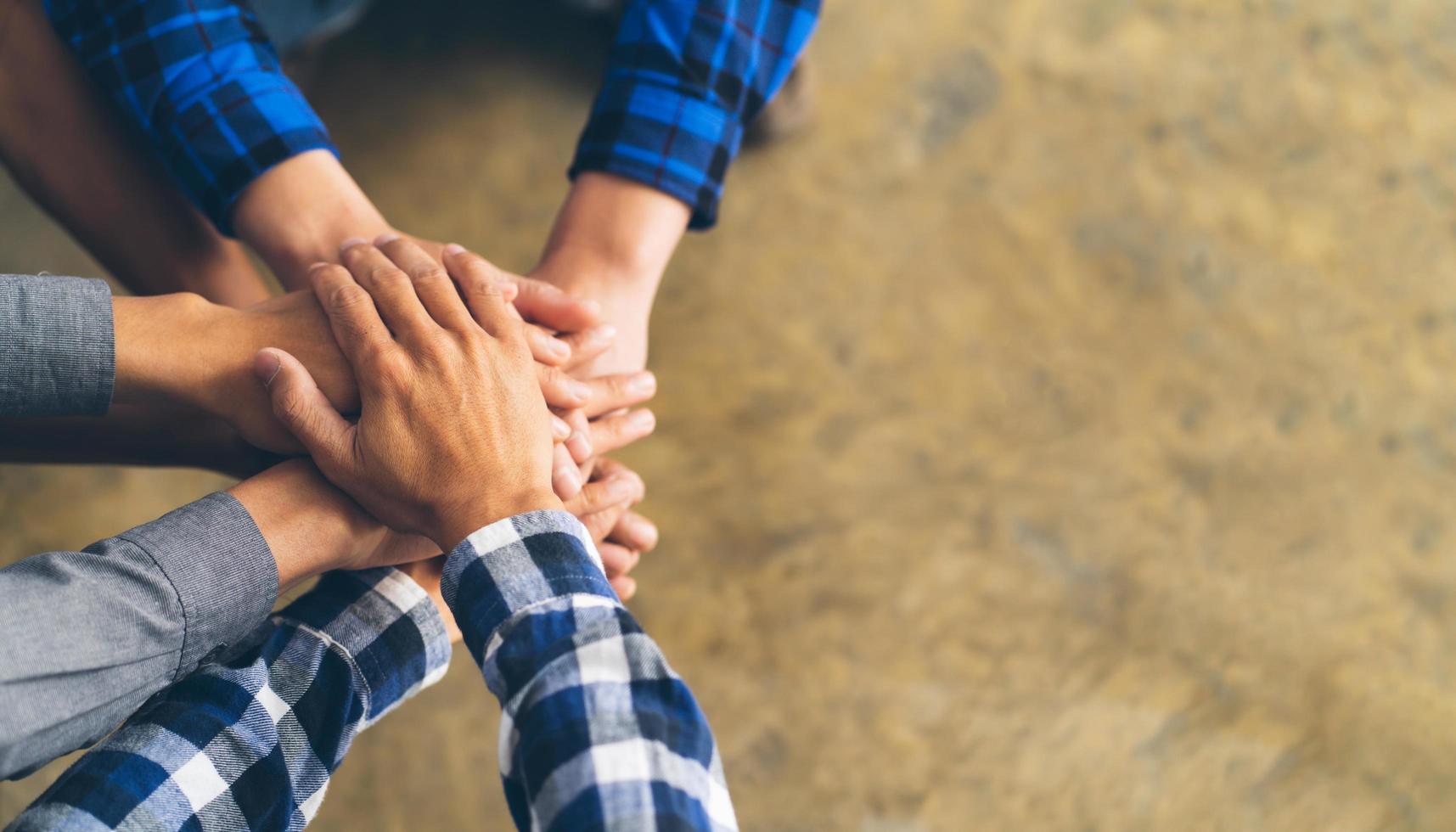 Close up top view of young people putting their hands together. Friends with stack of hands showing unity and teamwork, copy space. photo