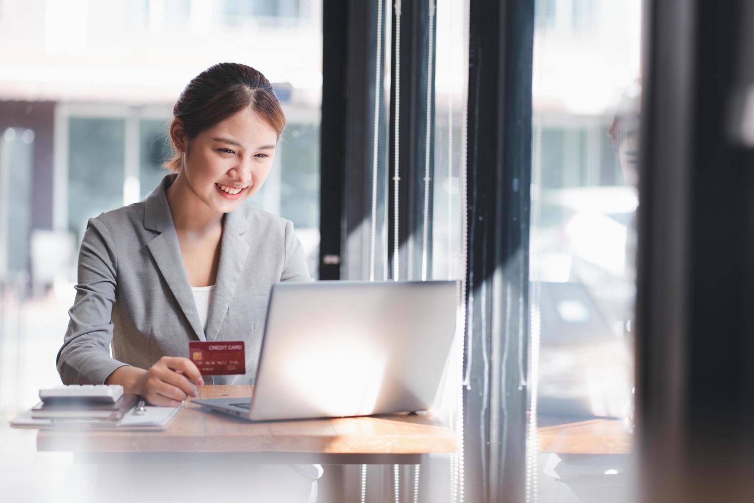 mujer asiática comprando en internet haciendo transacciones de pago instantáneas en la computadora usando tarjeta de crédito. foto