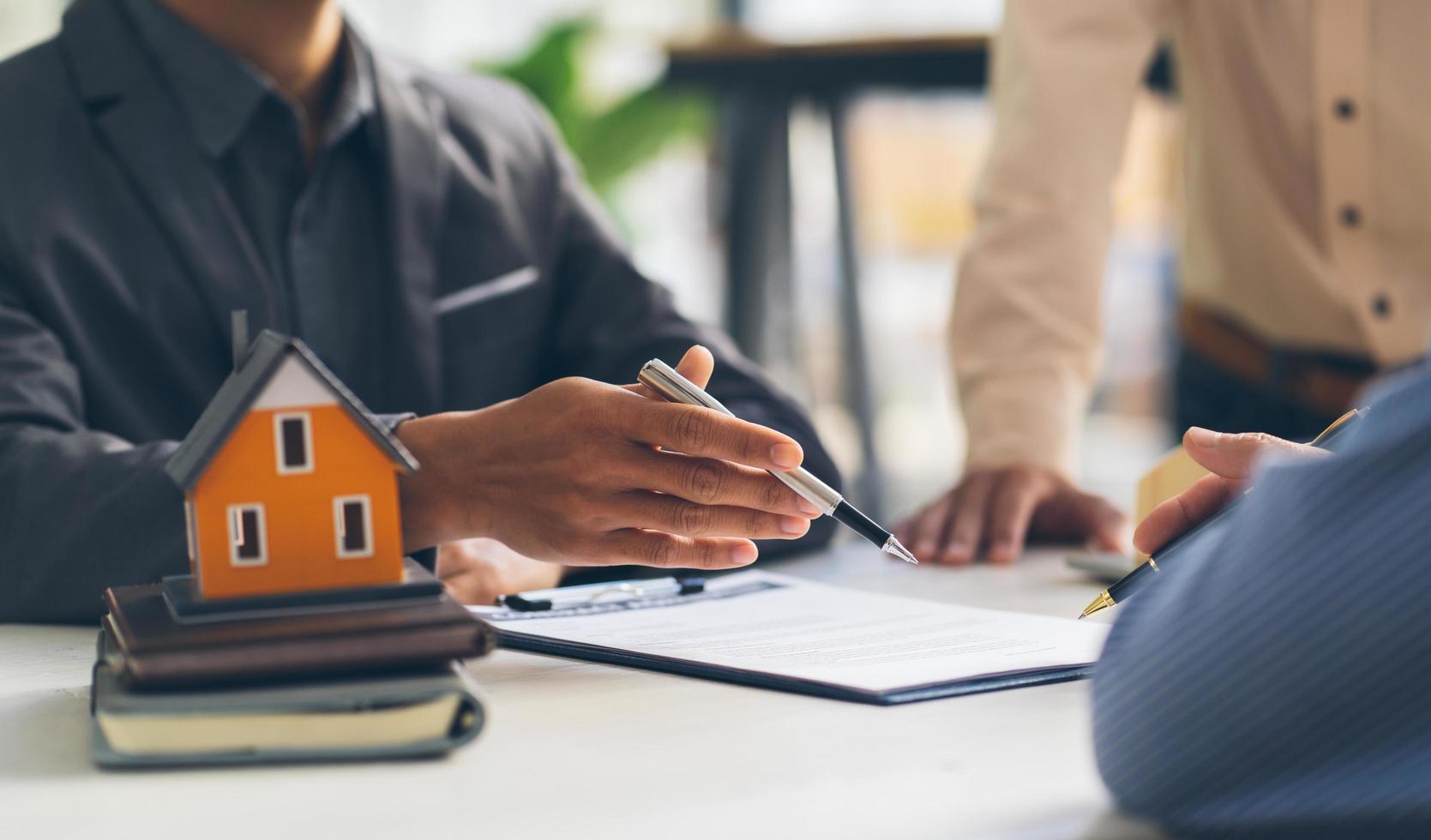 la casa de bienes raíces apunta a la firma del contrato de seguro y se lo explica a los clientes en la oficina. concepto de agencia de la casa. foto