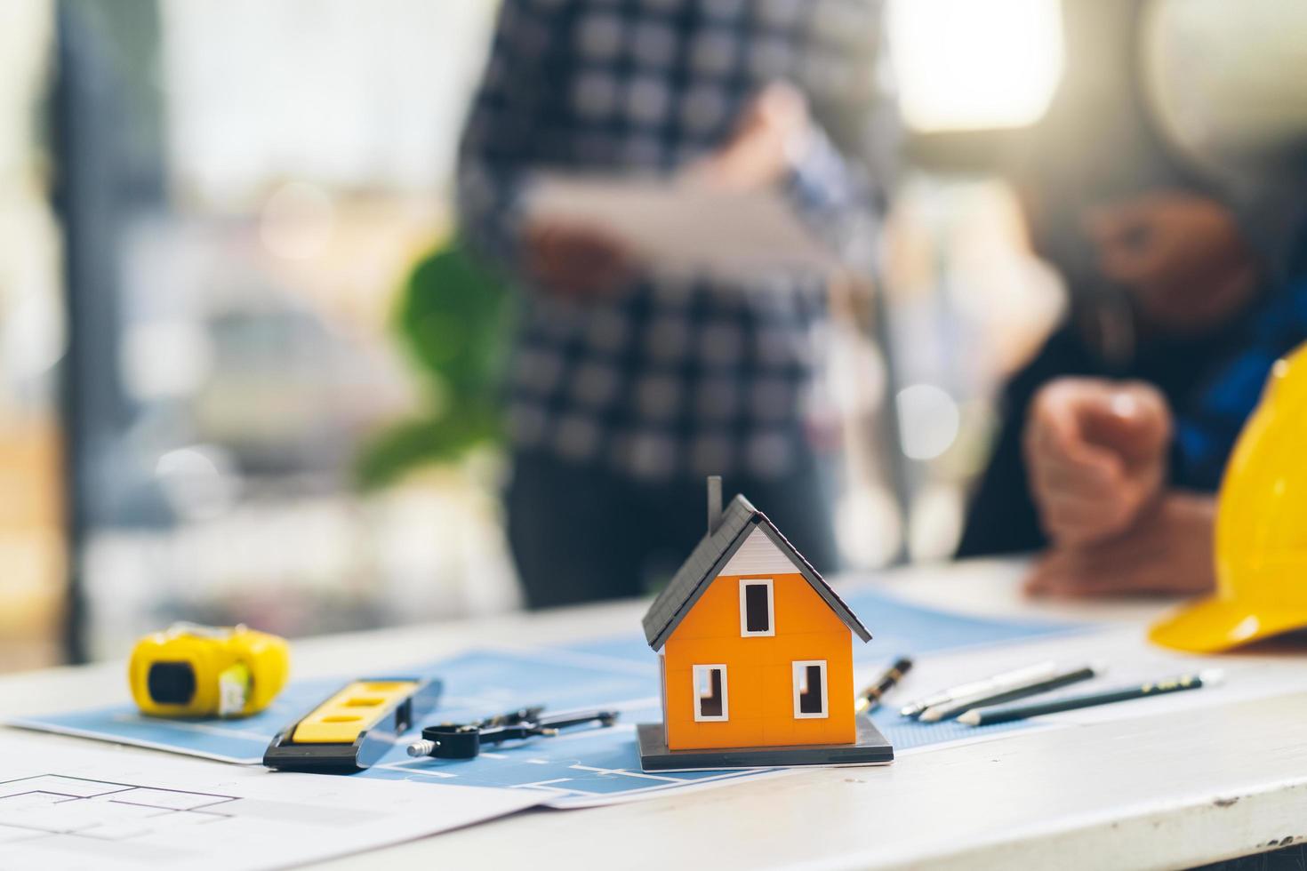 Architect and engineer meeting Planning for a New Project with construction equipment on table, Architect and engineer working with blueprint and house model. photo