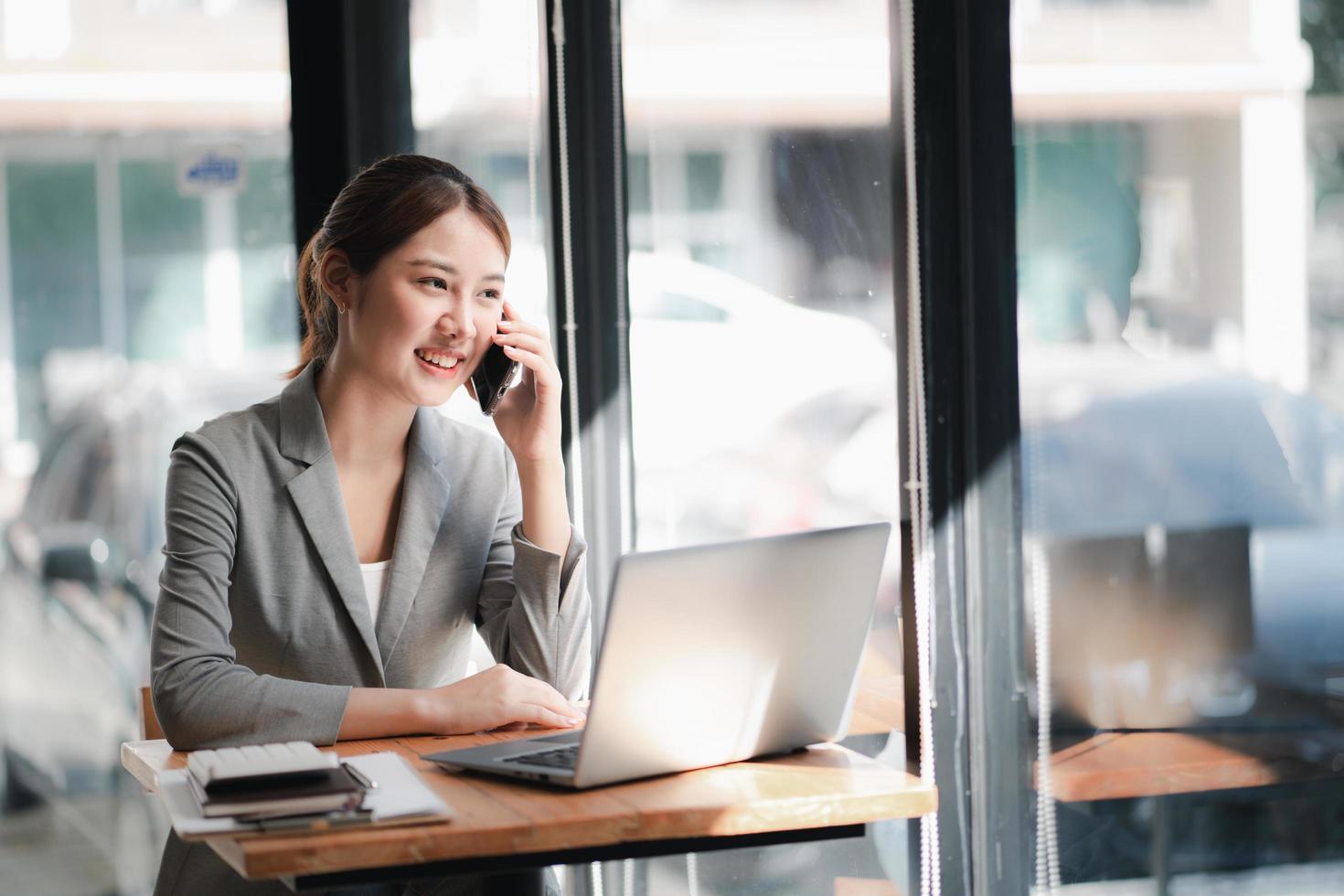 Portrait of young asian business woman talk on smartphone write notebook laptop in home office. Beautiful girl at desk computer take home order. Startup business asia woman online sme telemarketing. photo