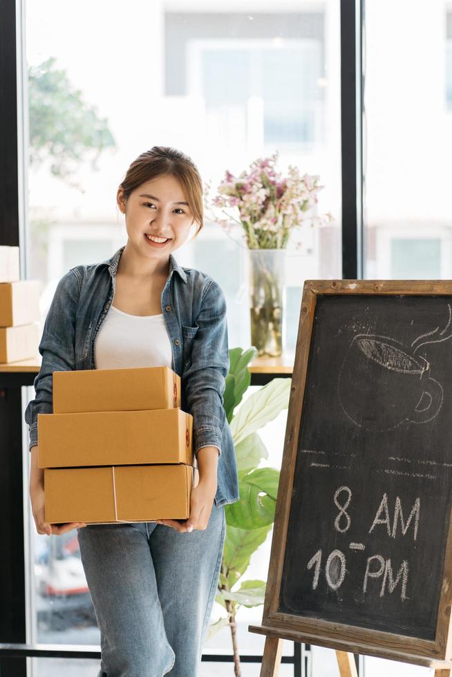 Asian woman start up small business owner packing cardboard box at workplace. freelance woman seller prepare parcel box of product for deliver to customer. Online selling, e-commerce. photo