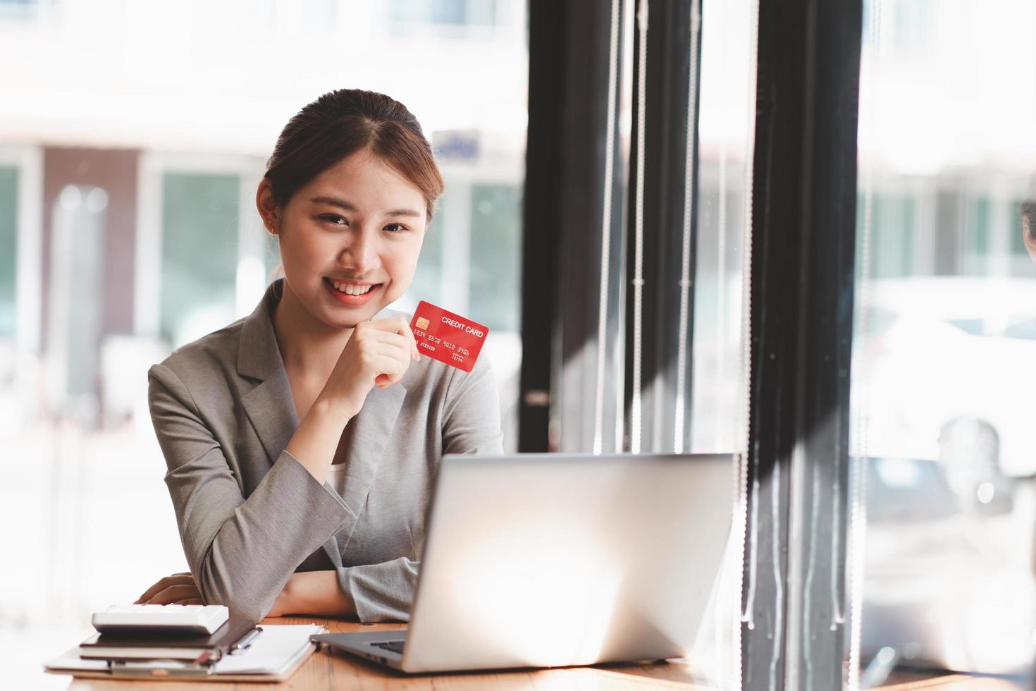 mujer joven con tarjeta de crédito y usando computadora portátil. empresaria trabajando en casa. compras en línea, comercio electrónico, banca por Internet, gastar dinero, trabajar desde el concepto de hogar foto