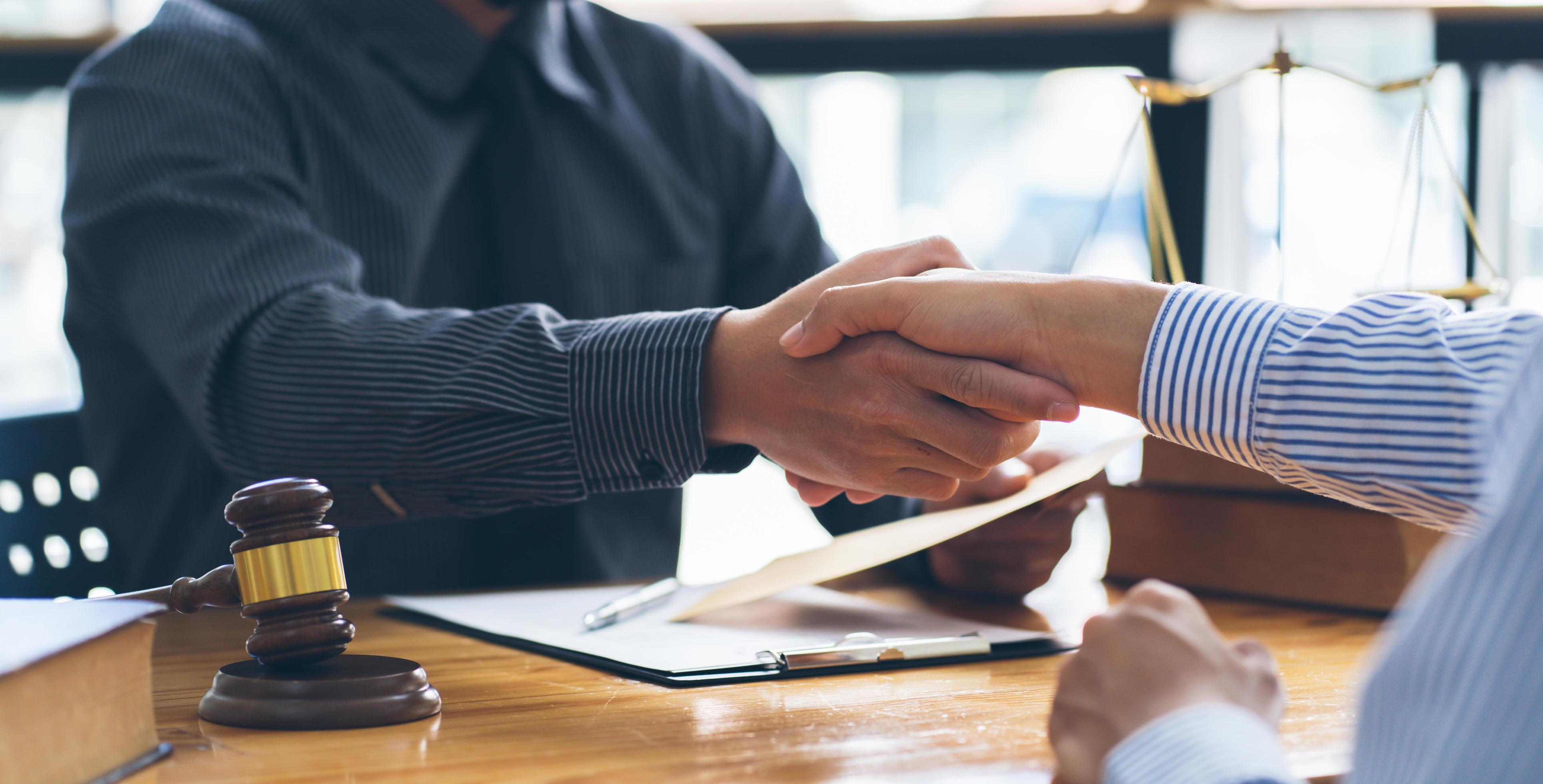 Businessmen shaking hands above the wooden desk in a modern office