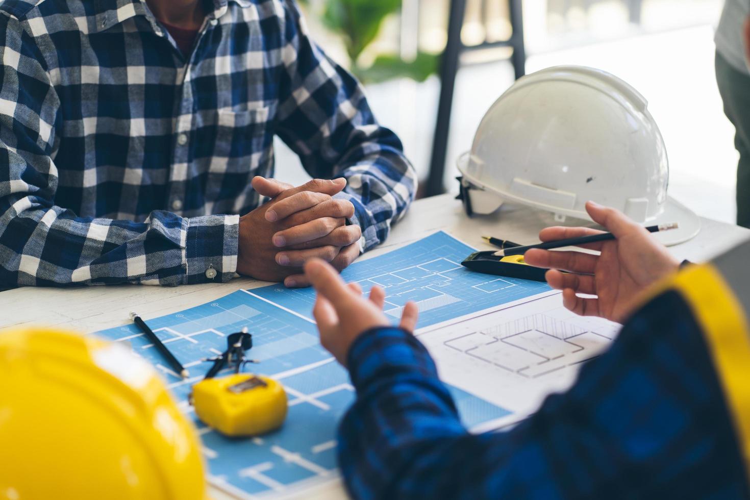 reunión de trabajo en equipo de ingenieros, trabajo de dibujo en la reunión de planos para el trabajo del proyecto con un socio en la construcción de modelos y herramientas de ingeniería en el concepto de sitio de trabajo, construcción y estructura. foto