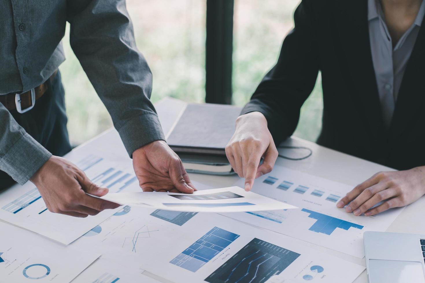 Close-up of Businessman hands pointing at turnover graph while discussing it on wooden desk with pen in meeting room, Business financial working concept, business people pointing at business document, photo