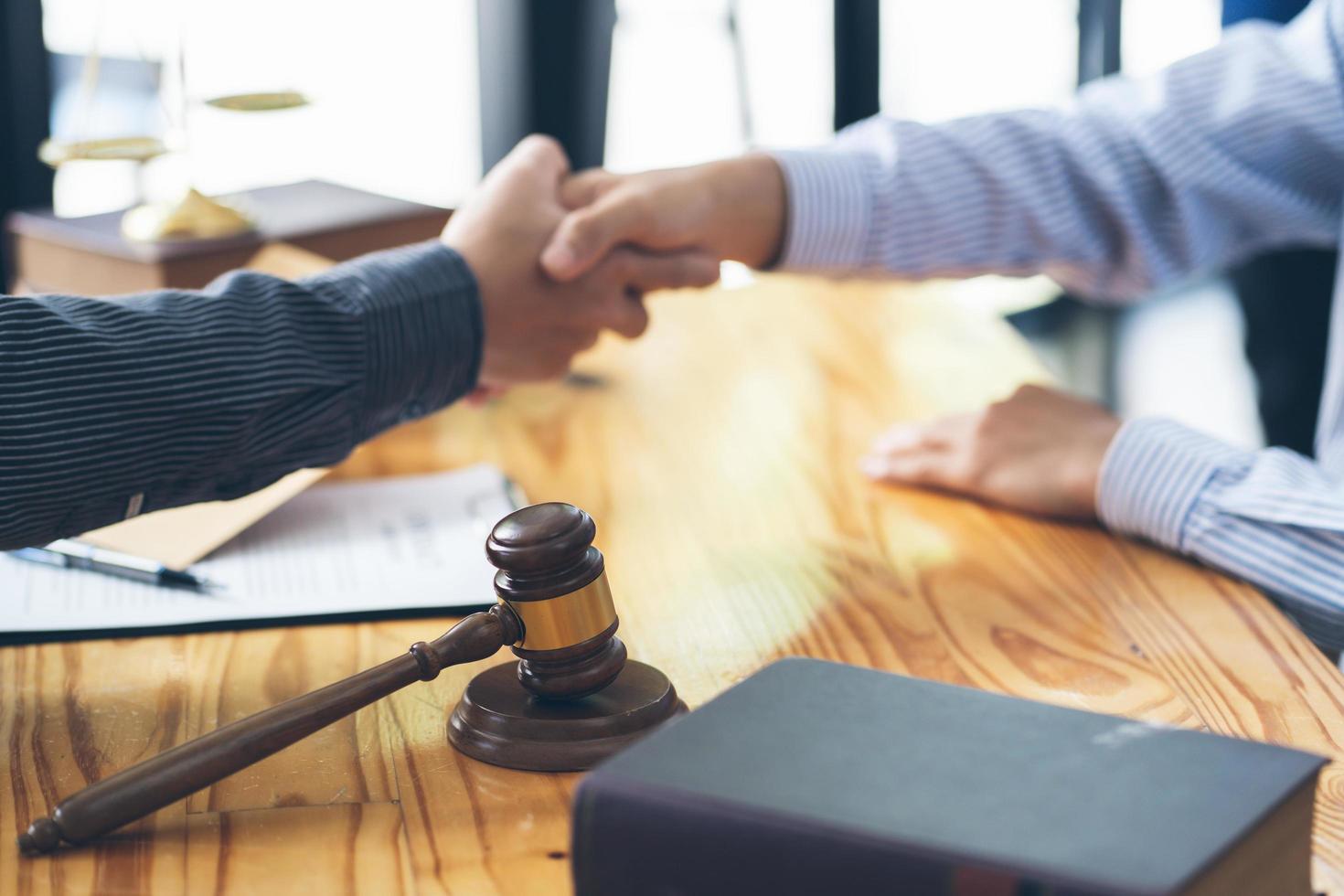 Businessmen shaking hands above the wooden desk in a modern office, close up. Unknown business people at meeting. Teamwork, partnership and handshake concept. photo