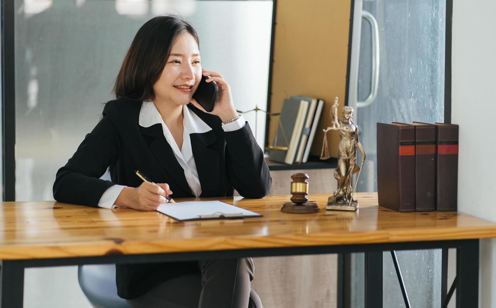 Young beautiful Asian woman lawyer who working in the office. Tlaking on a smart phone with client. photo