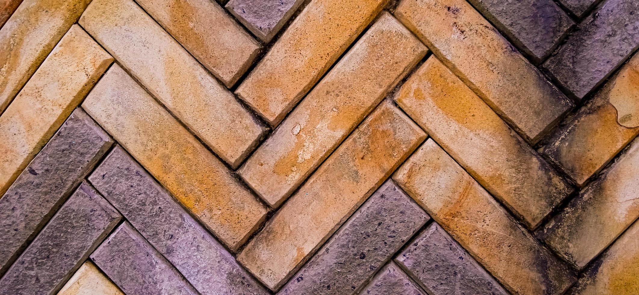 Yellow and orange zig zag brick tile pattern background with some green and brown moss grows on the brick surfaces. Available for text. Suitable for building, architecture, home decoration inspiration photo