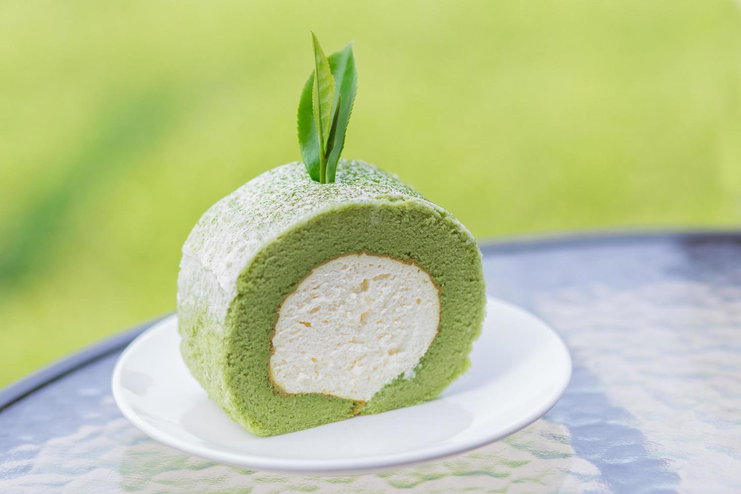 Green tea cake and roll with tea leaf  on white dish. photo