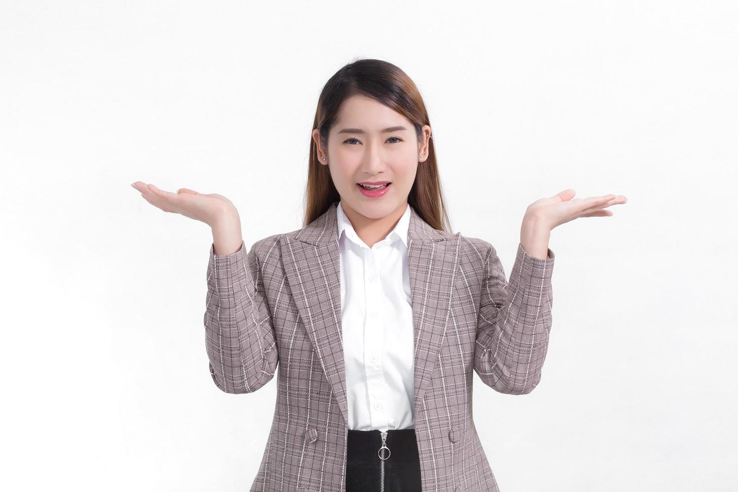 Asian working woman is smiling and shows her hands to present something on the white background. photo