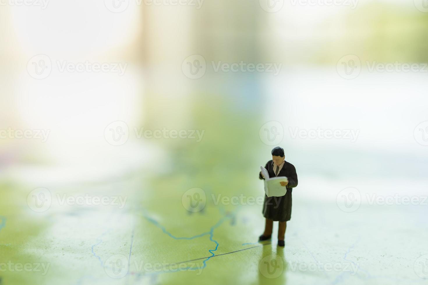 Global Business and Planning Concept. Close up of businessman miniature figure standing and reading newspaper on world map with copy space. photo
