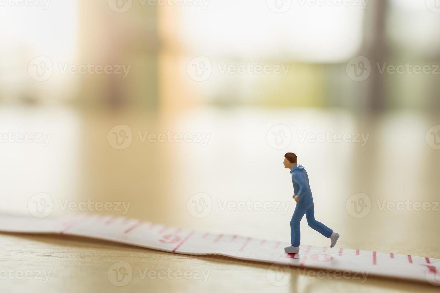 Sport and fitness concept. Close up of man runner miniature figure people running on measure tape on wooden table with copy space photo
