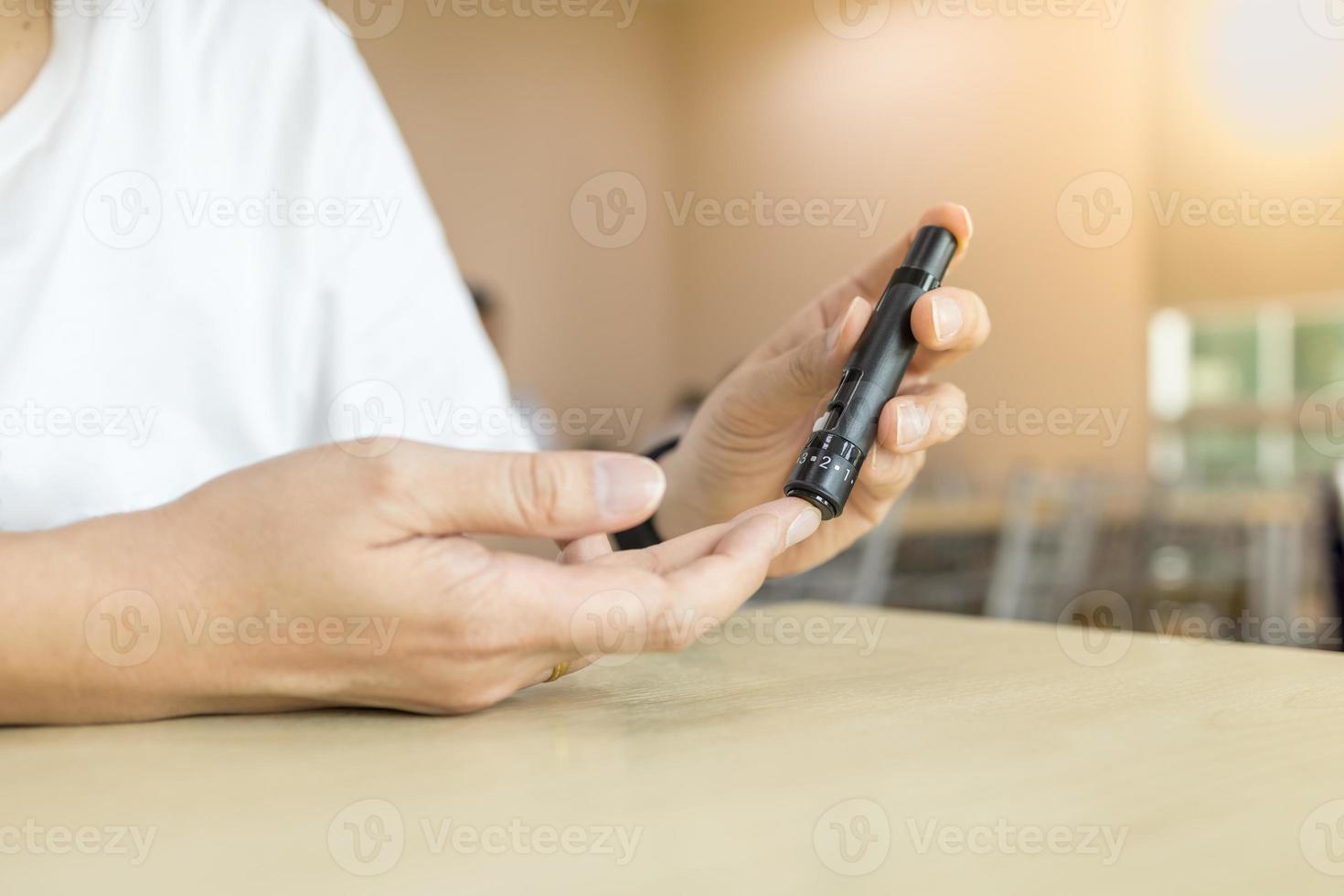 Close up of man hands using lancet on finger to check blood sugar level by Glucose meter. Use as Medicine, diabetes, glycemia, health care and people concept. photo