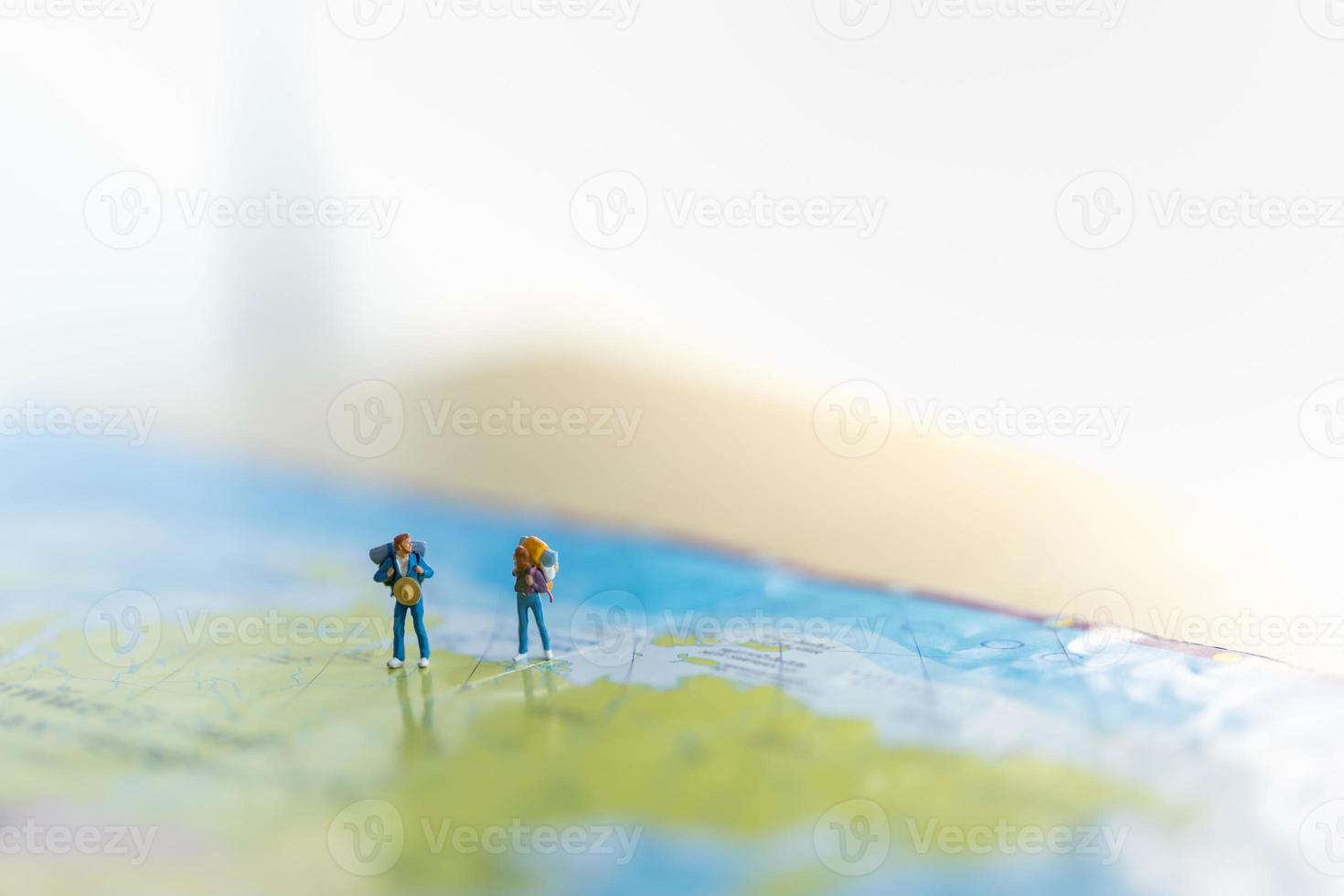 Travelling concepts. Two of miniature man and woman miniature figures with backpack standing on world map with copy space. photo