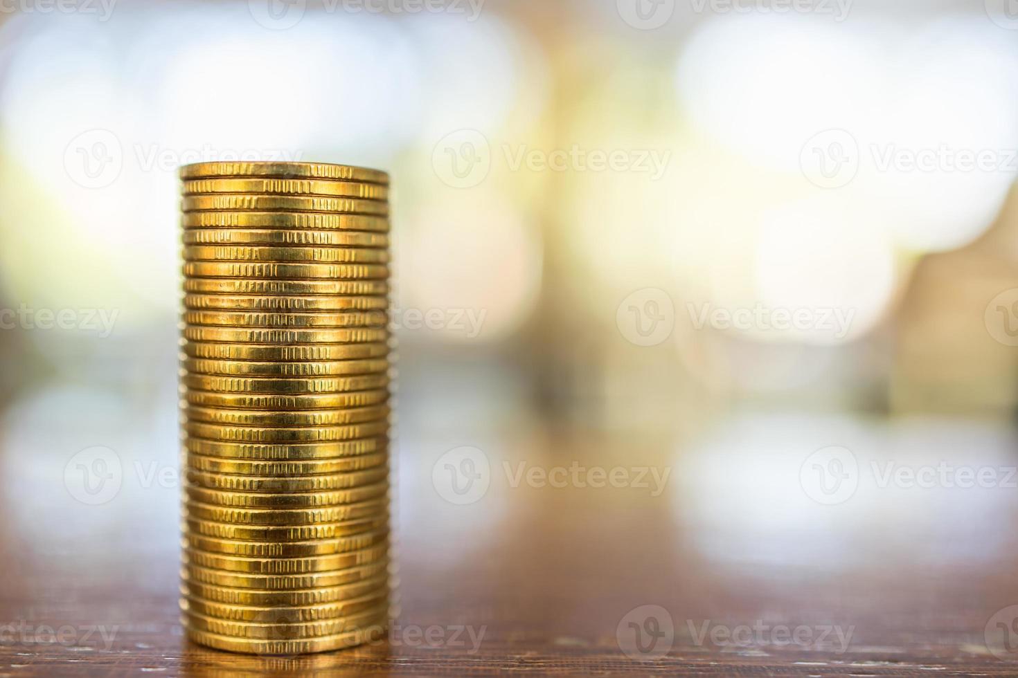 concepto de negocio, dinero, finanzas, seguridad y ahorro. primer plano de una pila de monedas de oro sobre una mesa de madera bajo la luz del sol con espacio para copiar. foto