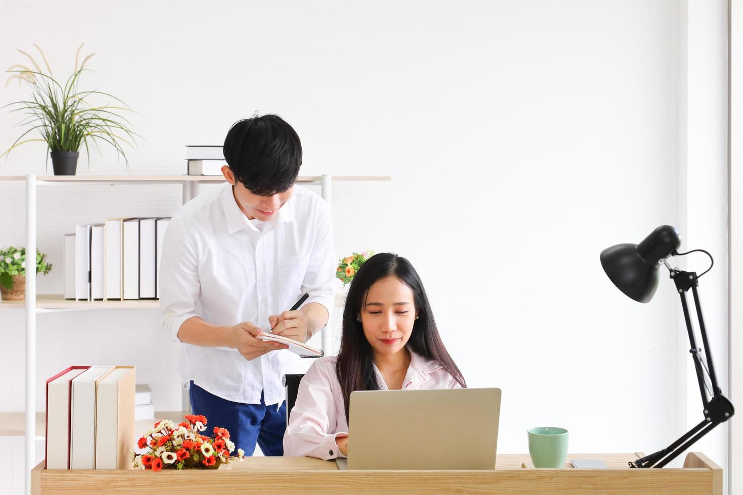 Young Asian couple spending time together at home office while working online from home with copy space photo