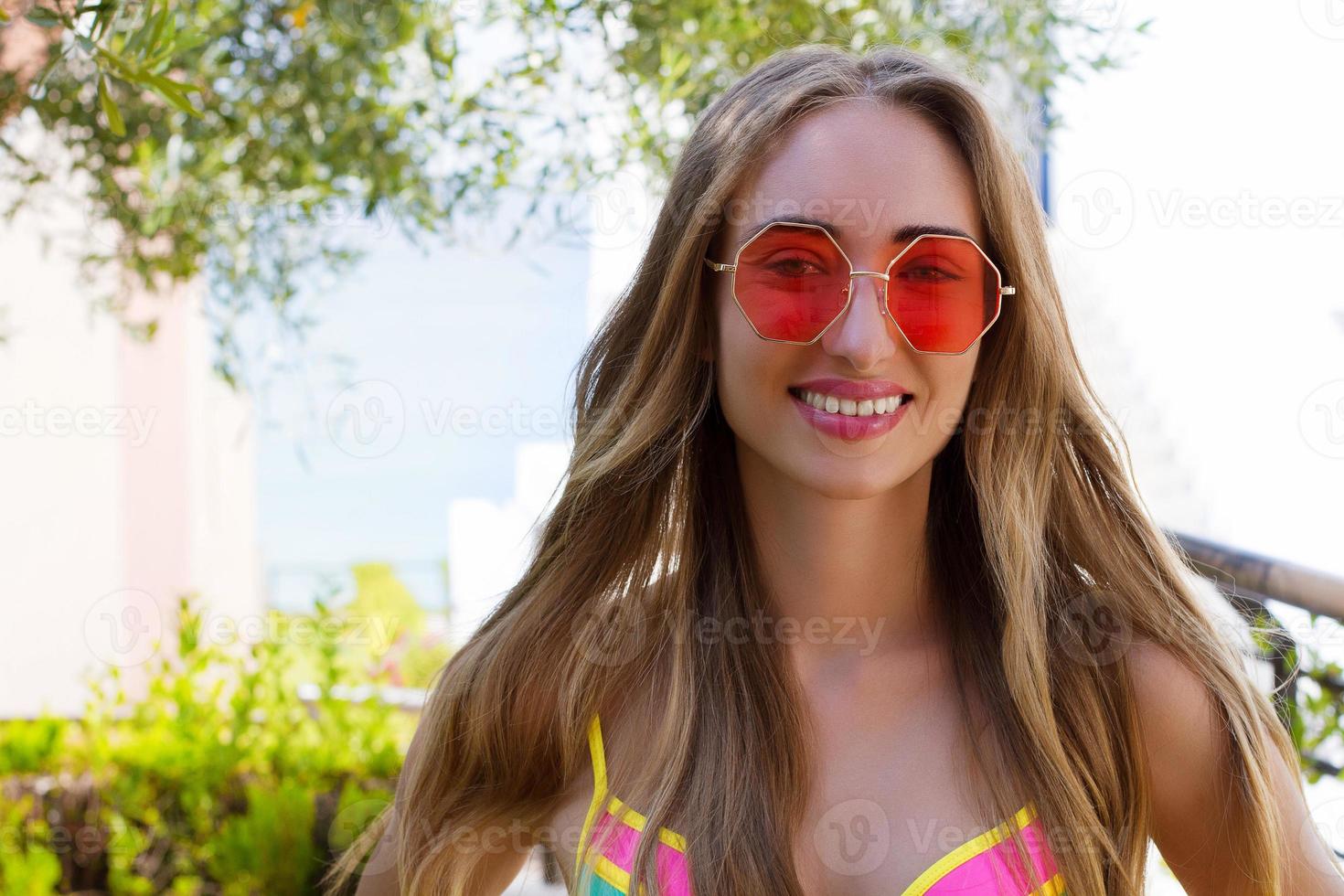 Close Up Happy Woman Face Summer Holidays. Summertime Smile Girl with Blond Hair at summer vacation in swim suit. Selective focus. Pink sunglasses photo