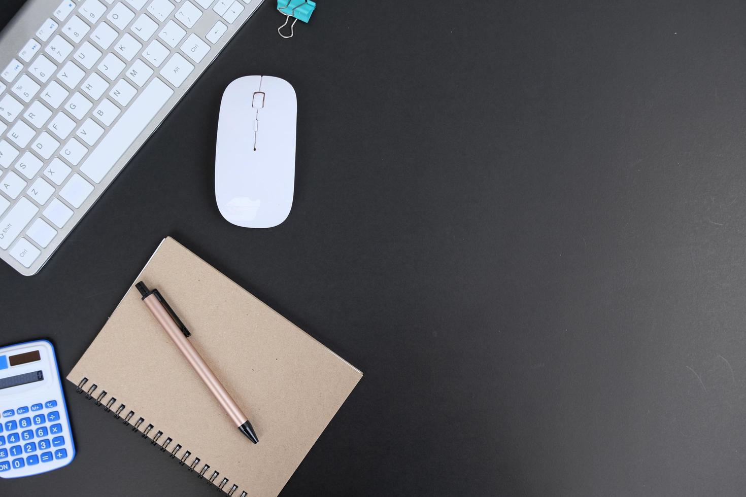 un cuaderno en blanco, un bolígrafo y anteojos están encima de una mesa de escritorio de oficina blanca. endecha plana, vista superior. mesa de escritorio de oficina de diseño blanco con computadora portátil, teléfono inteligente y suministros foto