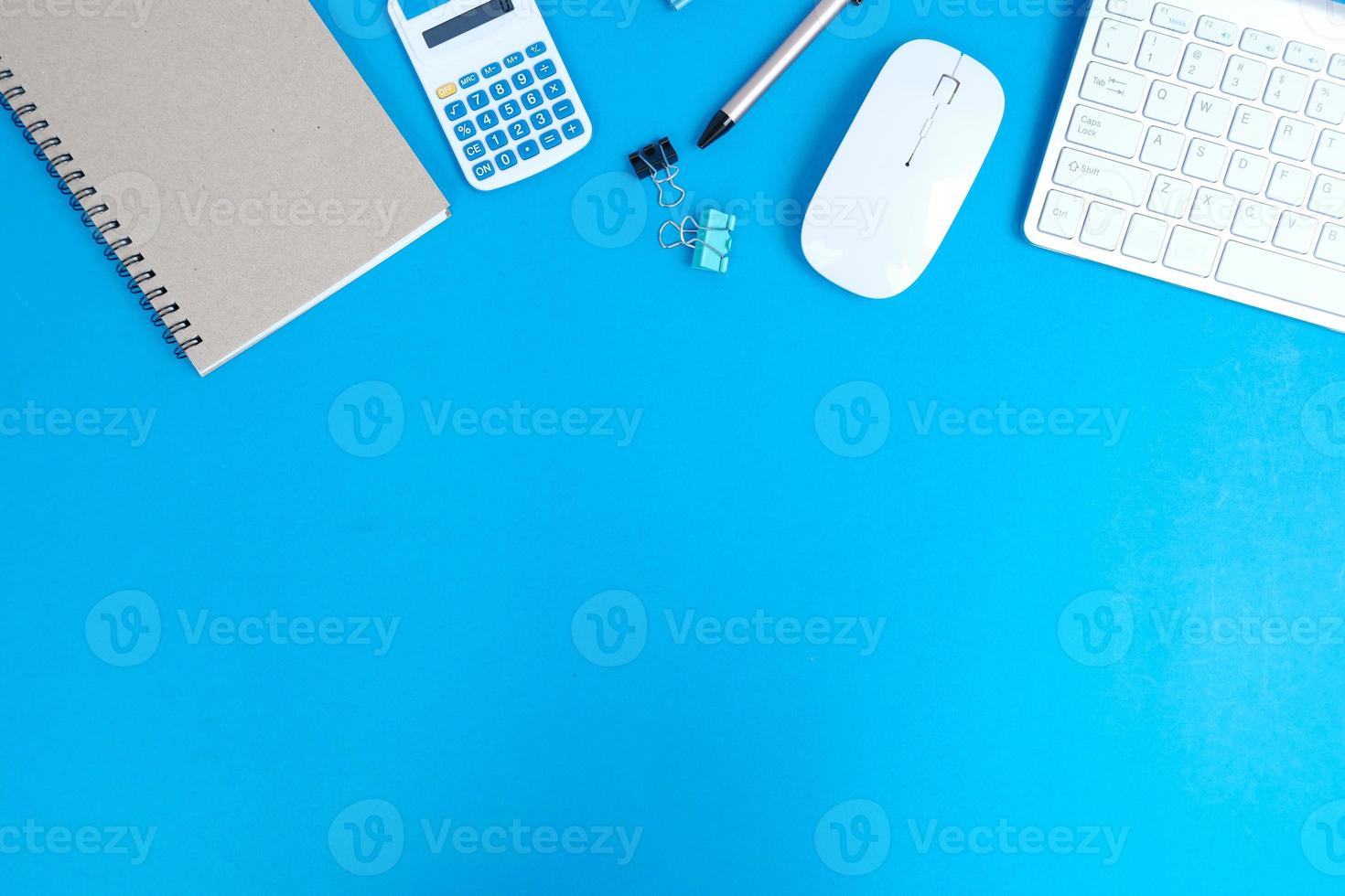 Blank notebook is in the middle of office desktable with pen and office supplies. Top view, flat lay. photo