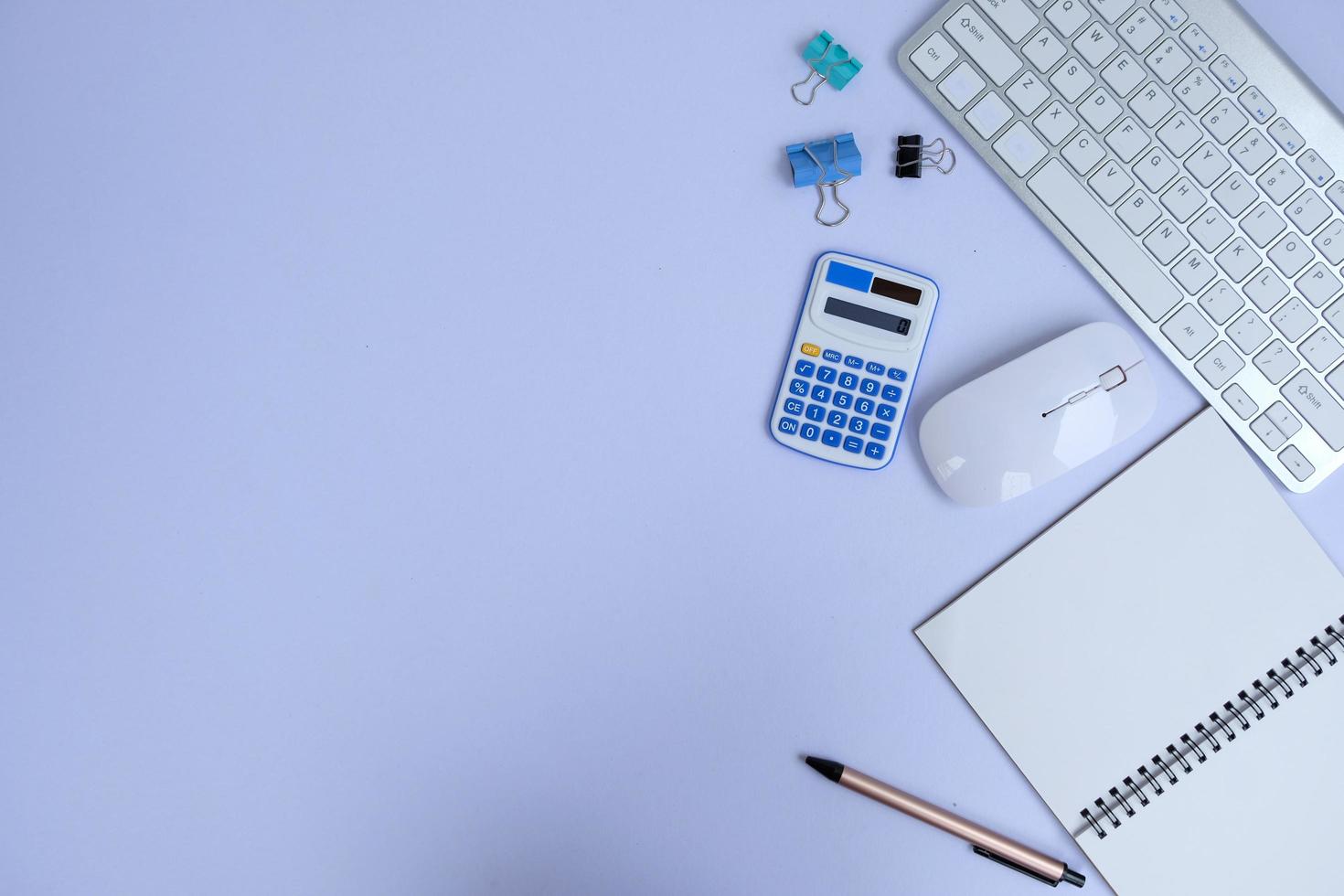 Blank notebook, a pen, and eyeglasses are on top of a white office desk table. Flat lay, top view. White designer office desk table with laptop, smartphone and supplies photo