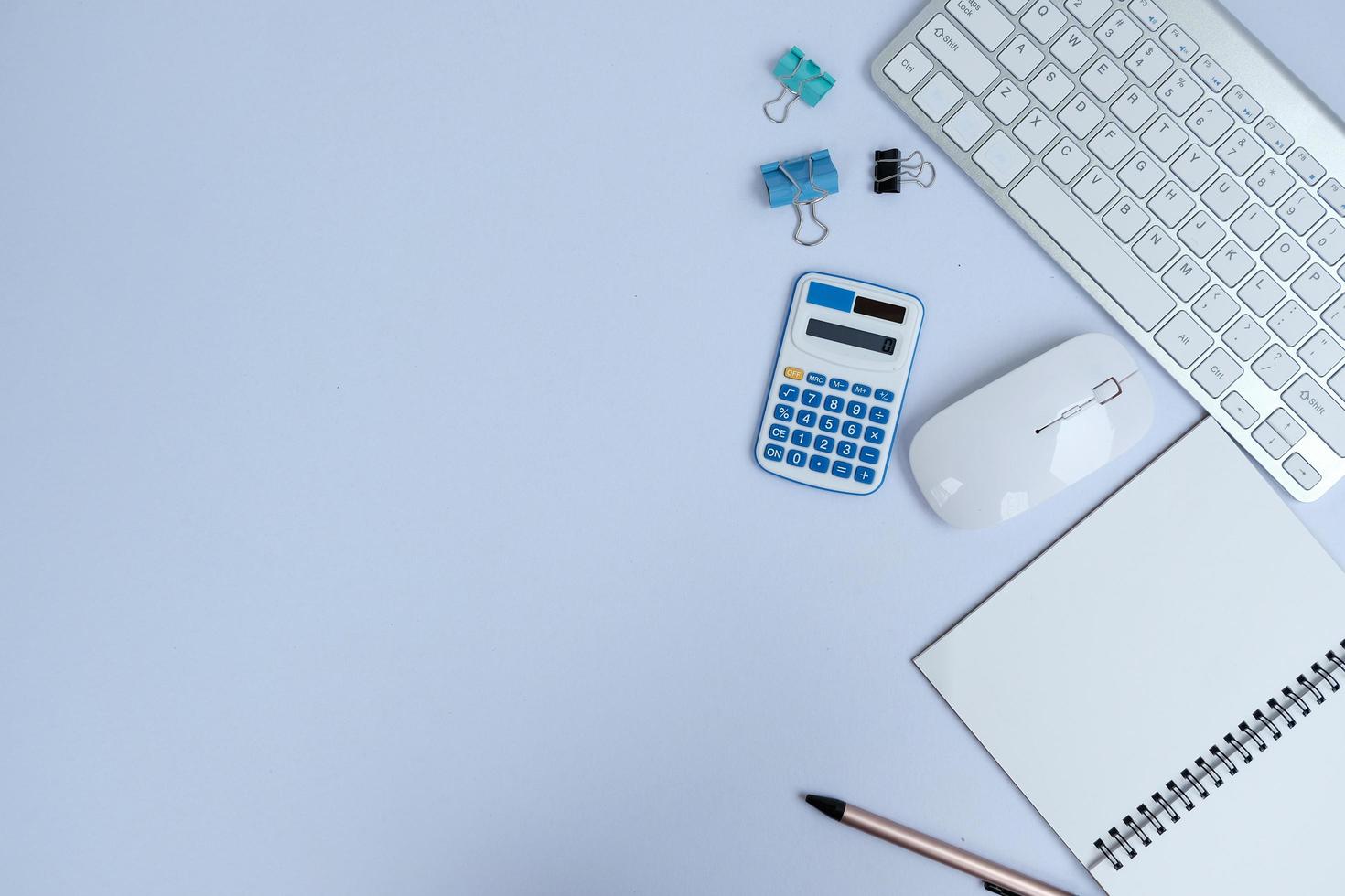 Blank notebook, a pen, and eyeglasses are on top of a white office desk table. Flat lay, top view. White designer office desk table with laptop, smartphone and supplies photo