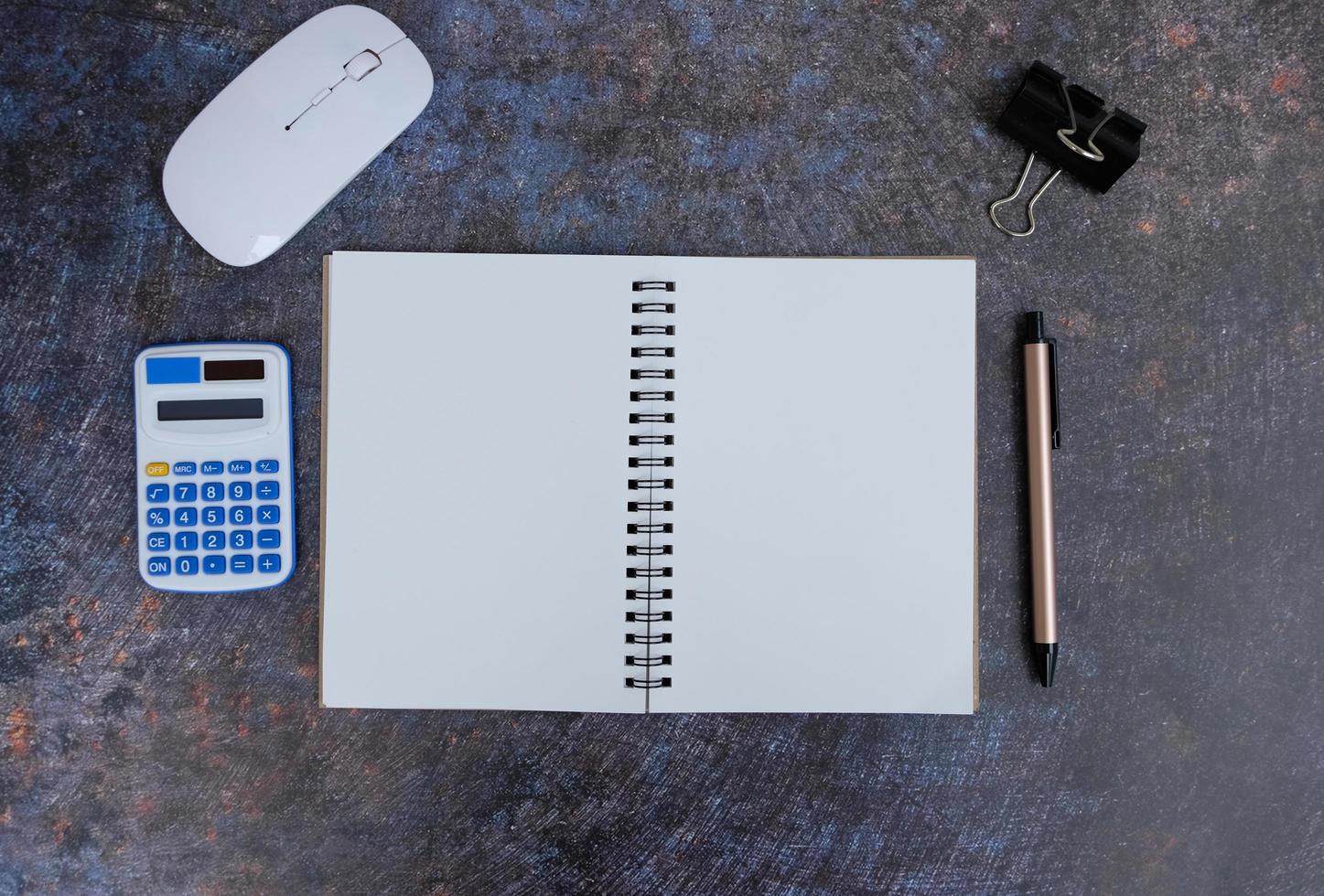 Blank notebook is in the middle of office desktable with pen and office supplies. Top view, flat lay. photo