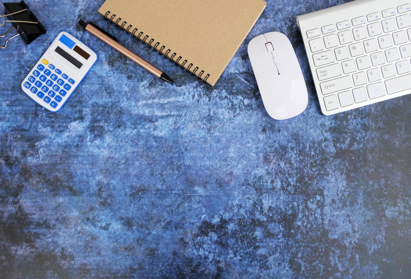 Blank notebook is in the middle of office desktable with pen and office supplies. Top view, flat lay. photo