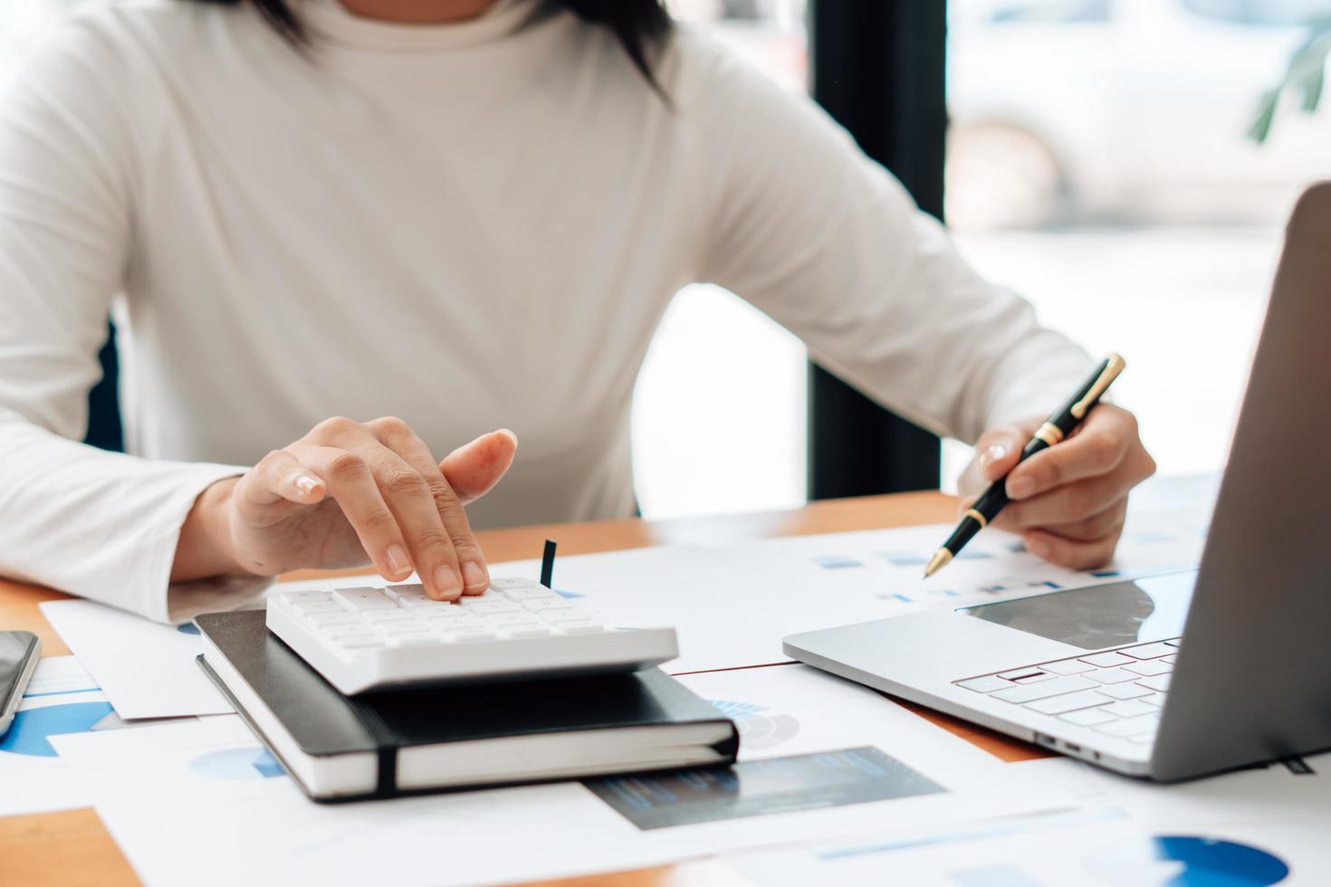 Close up Businessman and partner using calculator and laptop for calaulating finance, tax, accounting, statistics and analytic research concept photo