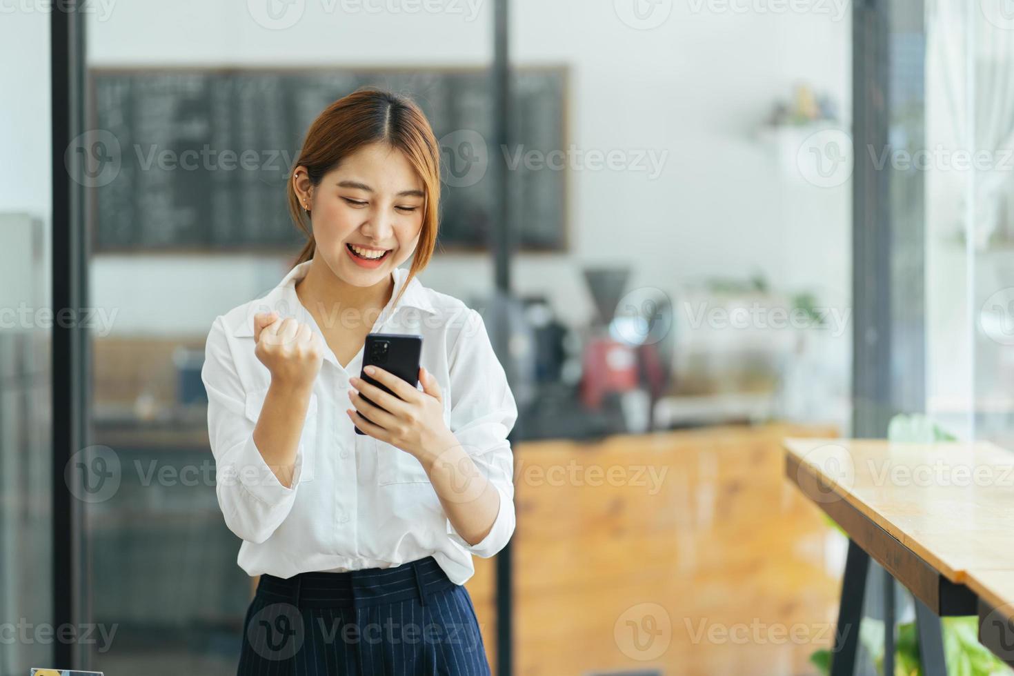 la mujer de negocios asiática con ropa informal de oficina es feliz y alegre mientras se comunica con su teléfono inteligente. foto