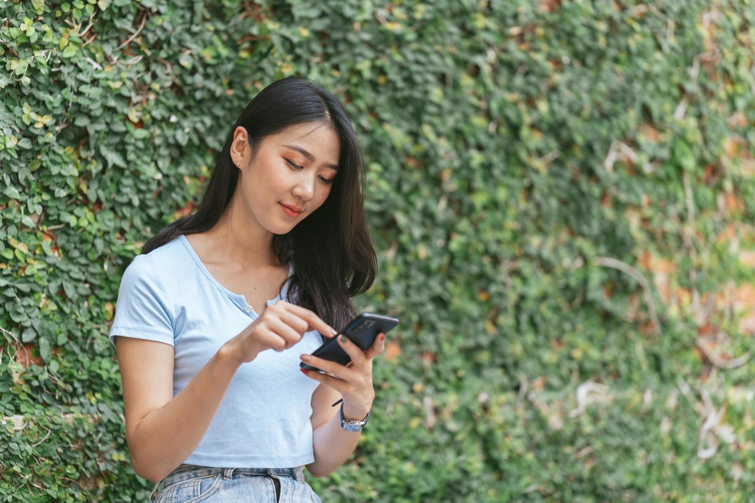 Happy asian woman smiling and holding cellphone while sitting in street summer cafe. photo