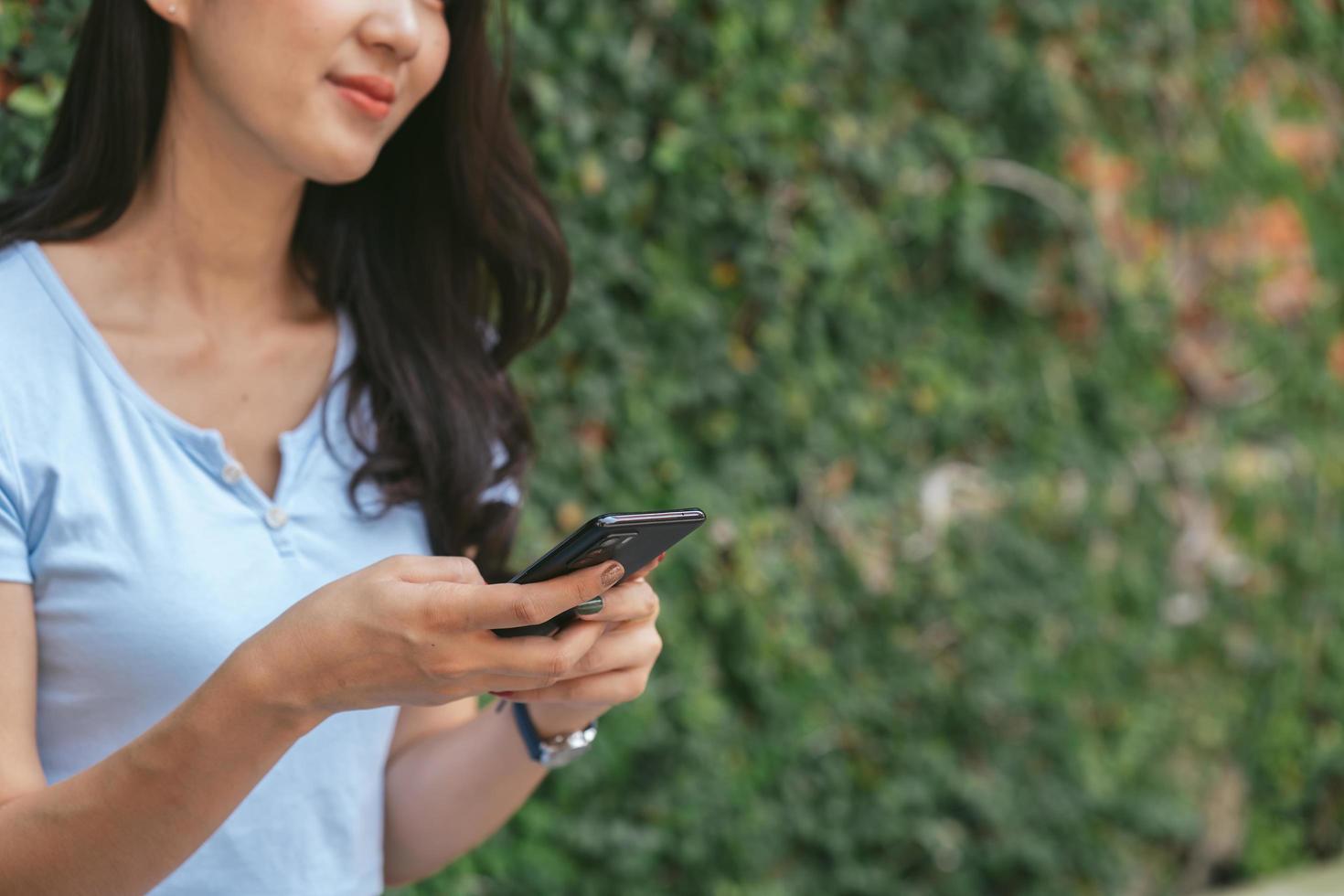 Happy asian woman smiling and holding cellphone while sitting in street summer cafe. photo