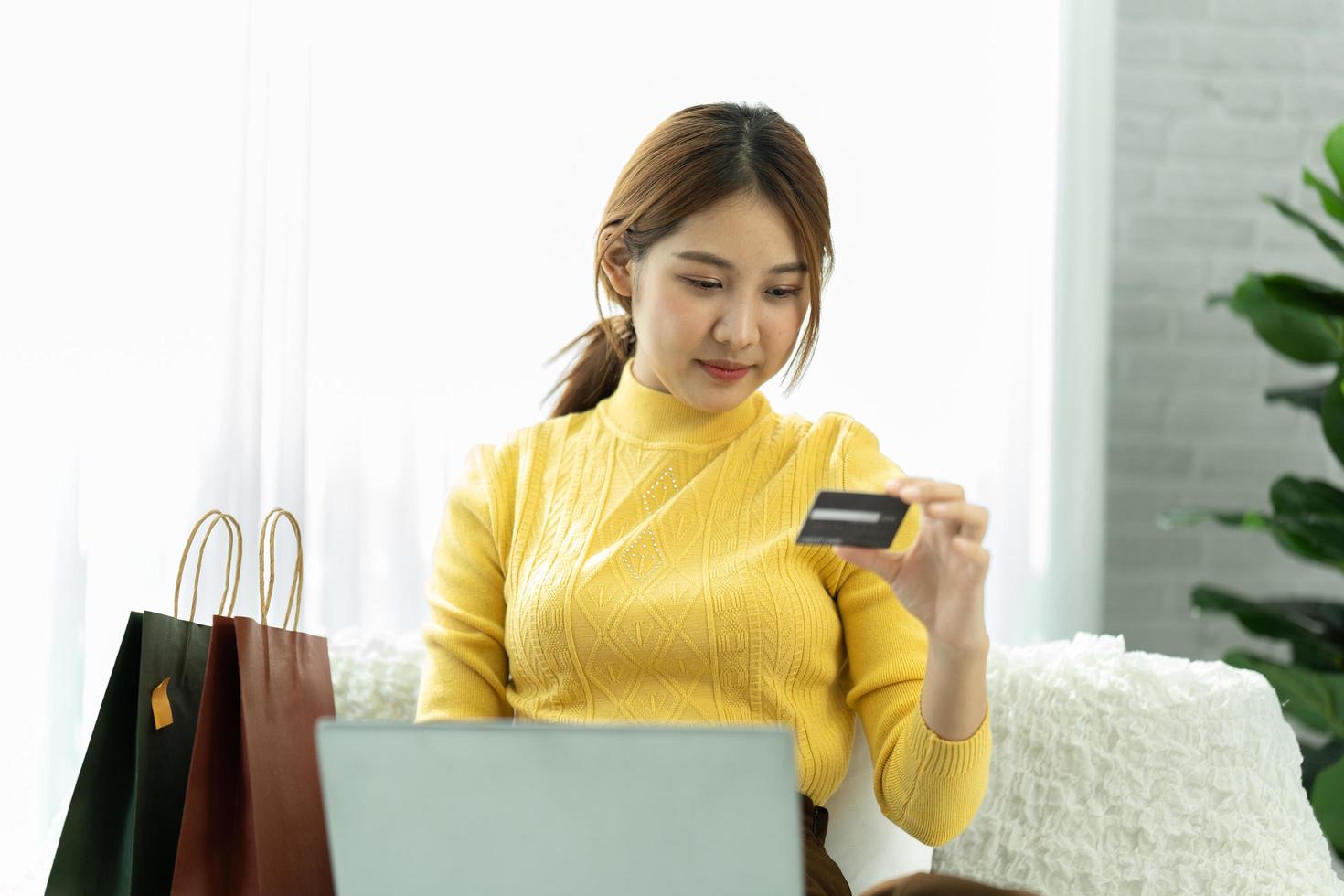 la mujer asiática con ropa informal es feliz y alegre mientras se comunica con su teléfono inteligente y trabaja en una cafetería. foto