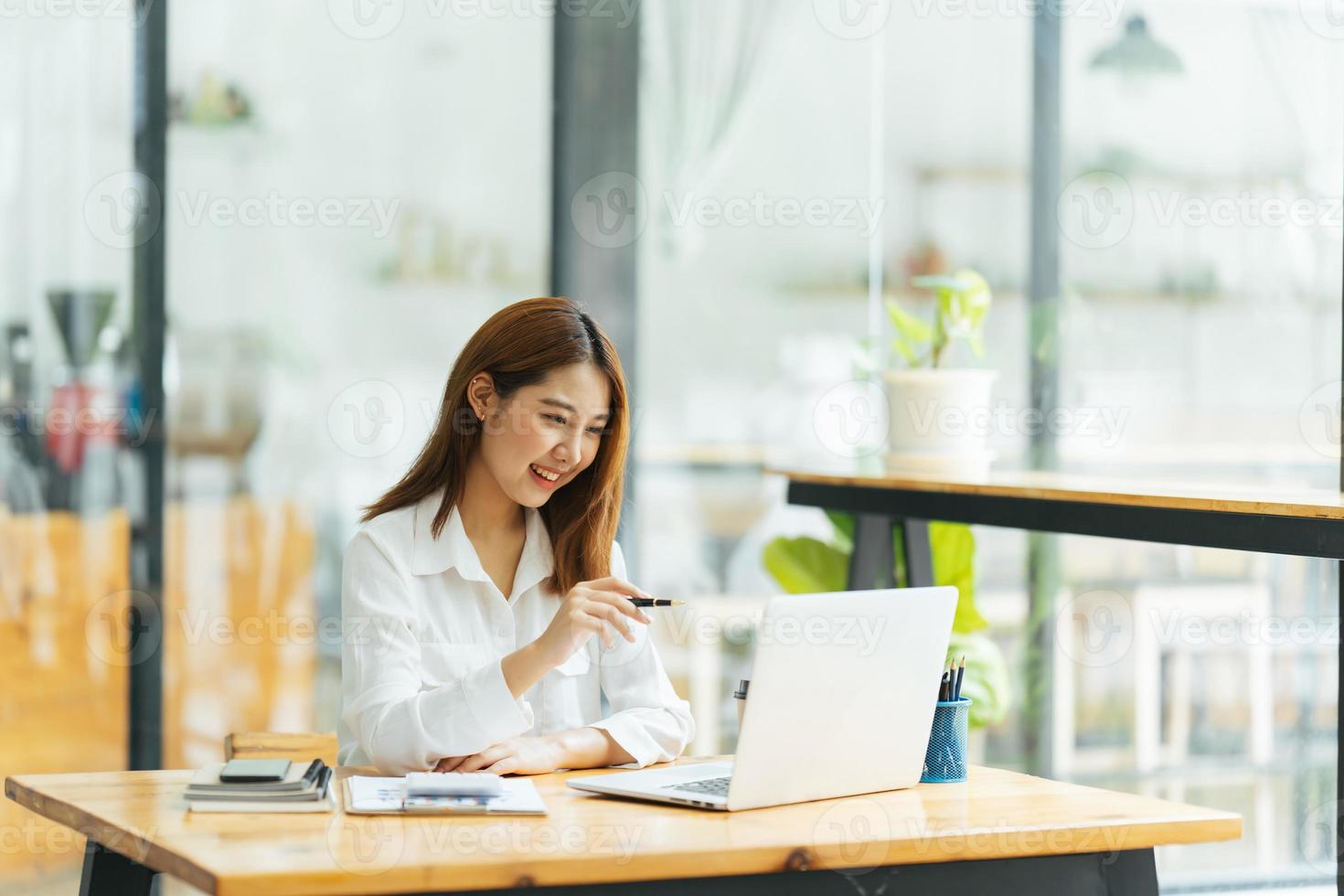 reunión en línea. mujer joven feliz usando computadora portátil para conferencias virtuales, haciendo videollamadas en casa. alegre mujer asiática comunicándose con colegas, amigos de forma remota. foto