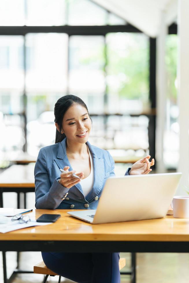 Asian female talking about sale report in video conference. Asian team using laptop and tablet online meeting in video call.Working from home remotely. photo