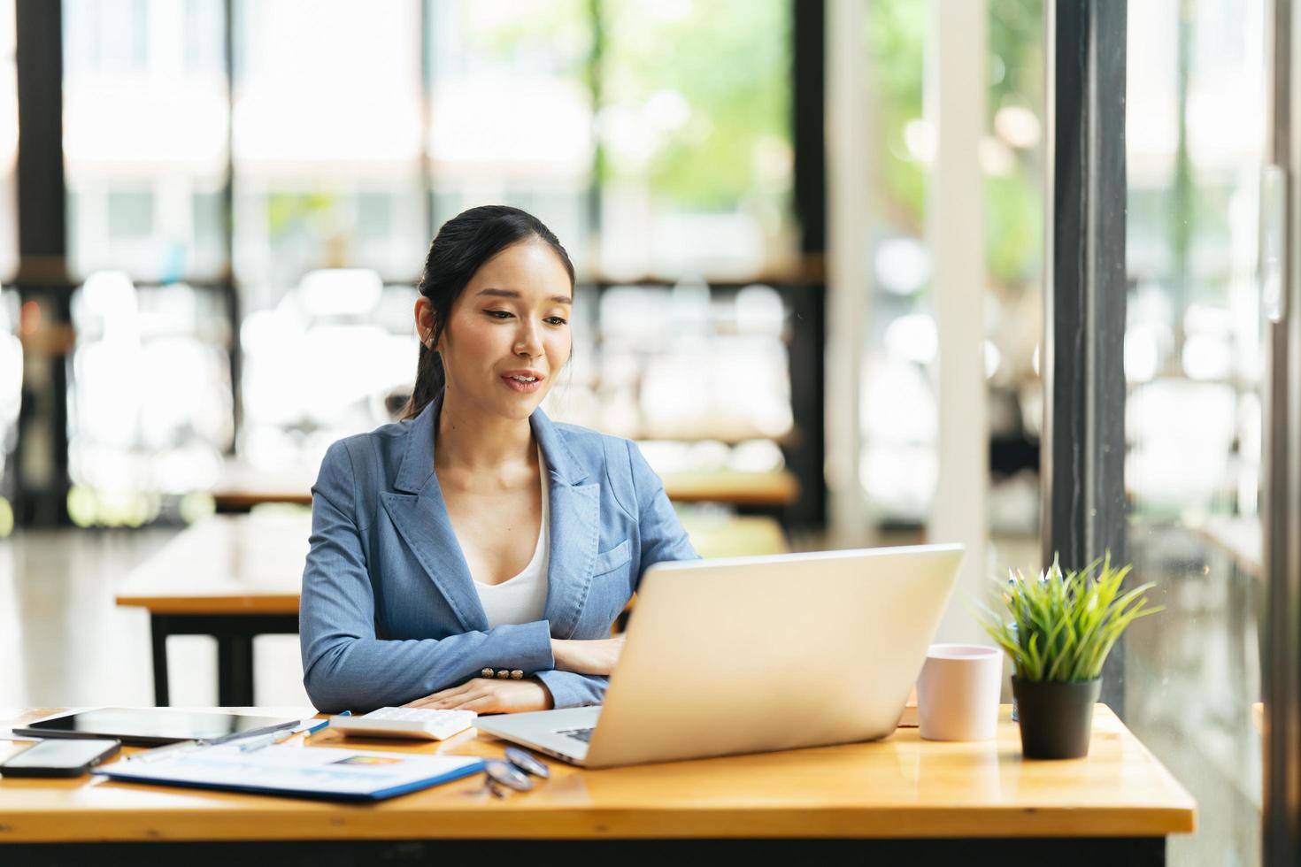 Asian female talking about sale report in video conference. Asian team using laptop and tablet online meeting in video call.Working from home remotely. photo