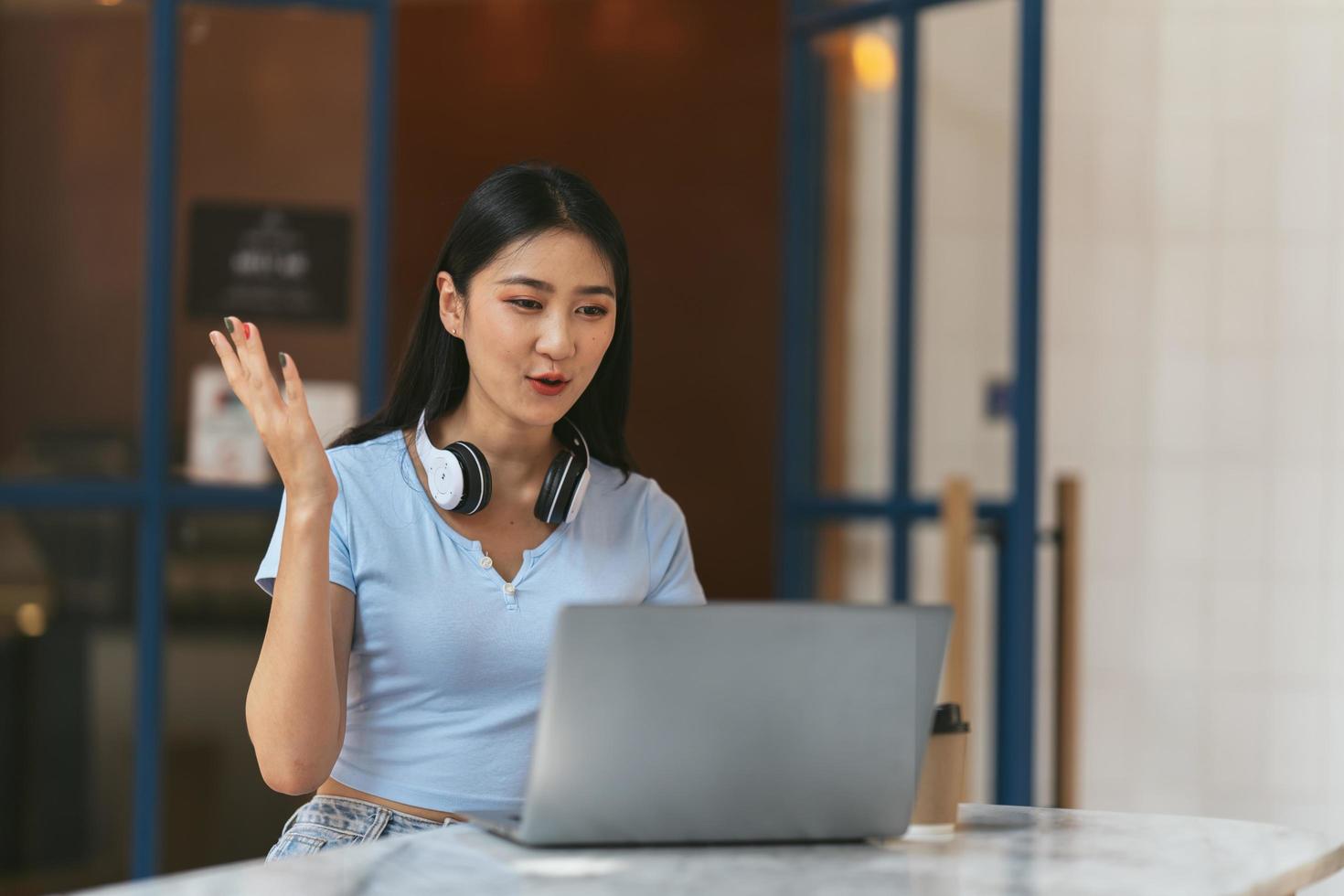 Asian woman having video call on her computer at home. Smiling girl studying online with teacher. photo