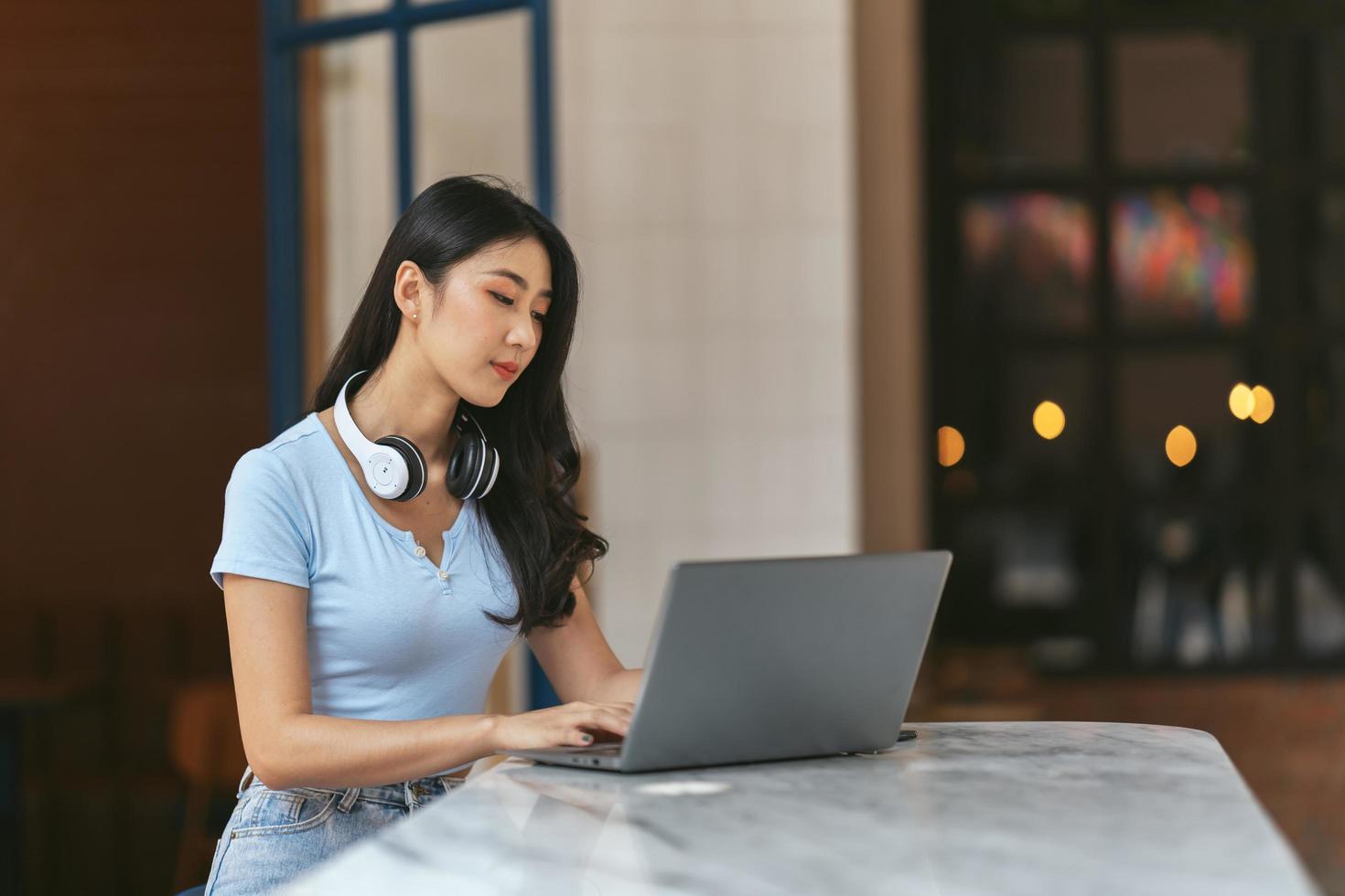 joven estudiante asiática sentada en la mesa, usando auriculares cuando estudia. foto