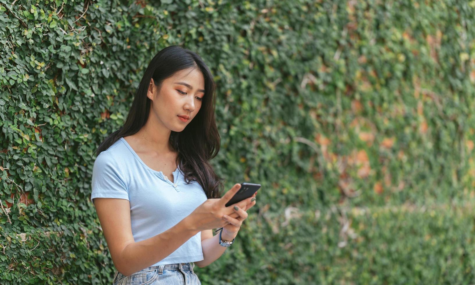 Happy asian woman smiling and holding cellphone while sitting in street summer cafe. photo