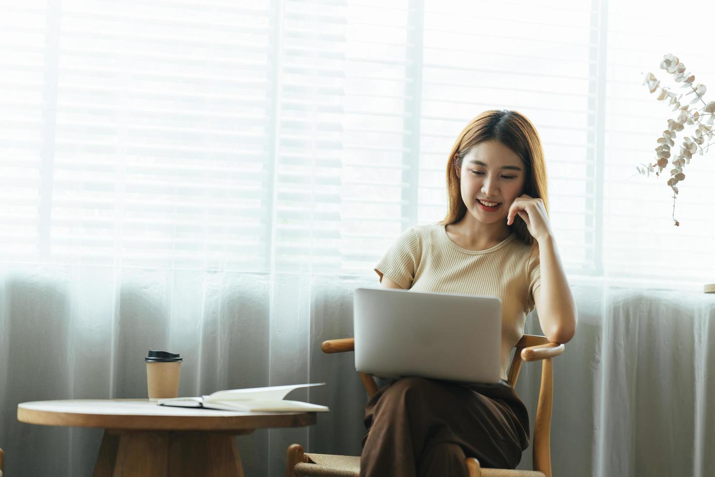 Portrait of Asian young female working on laptop and financial report at coffee shop. photo