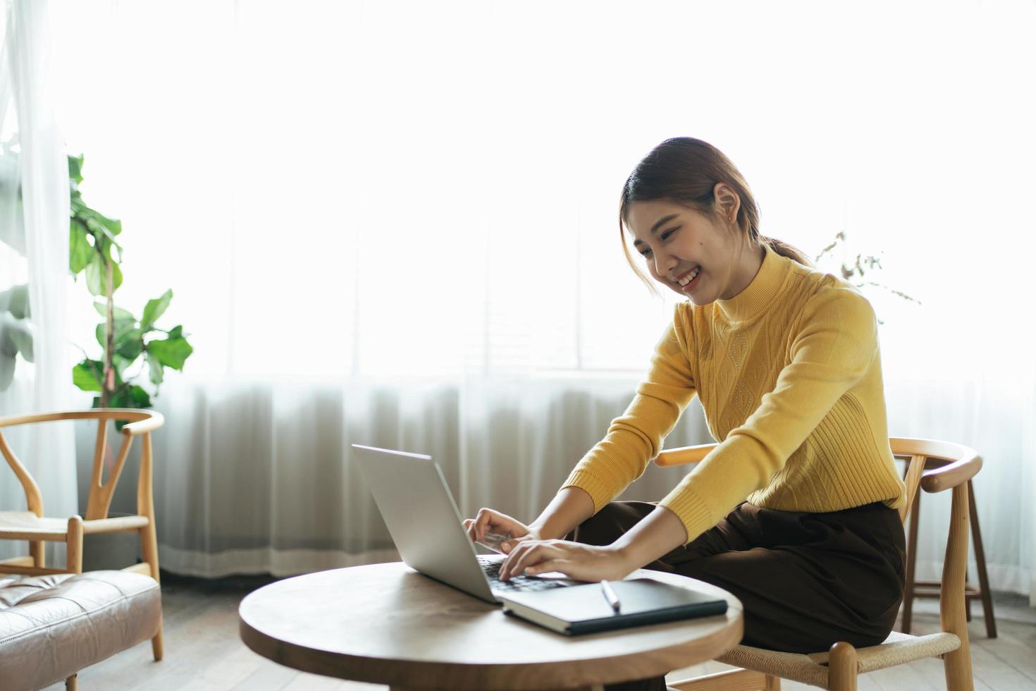 Portrait of beautiful Asian woman sitting indoors at coffee shop restaurant during summer, using smart wireless technology computer laptop and smartphone, relaxing coffee break at cafe restaurant. photo